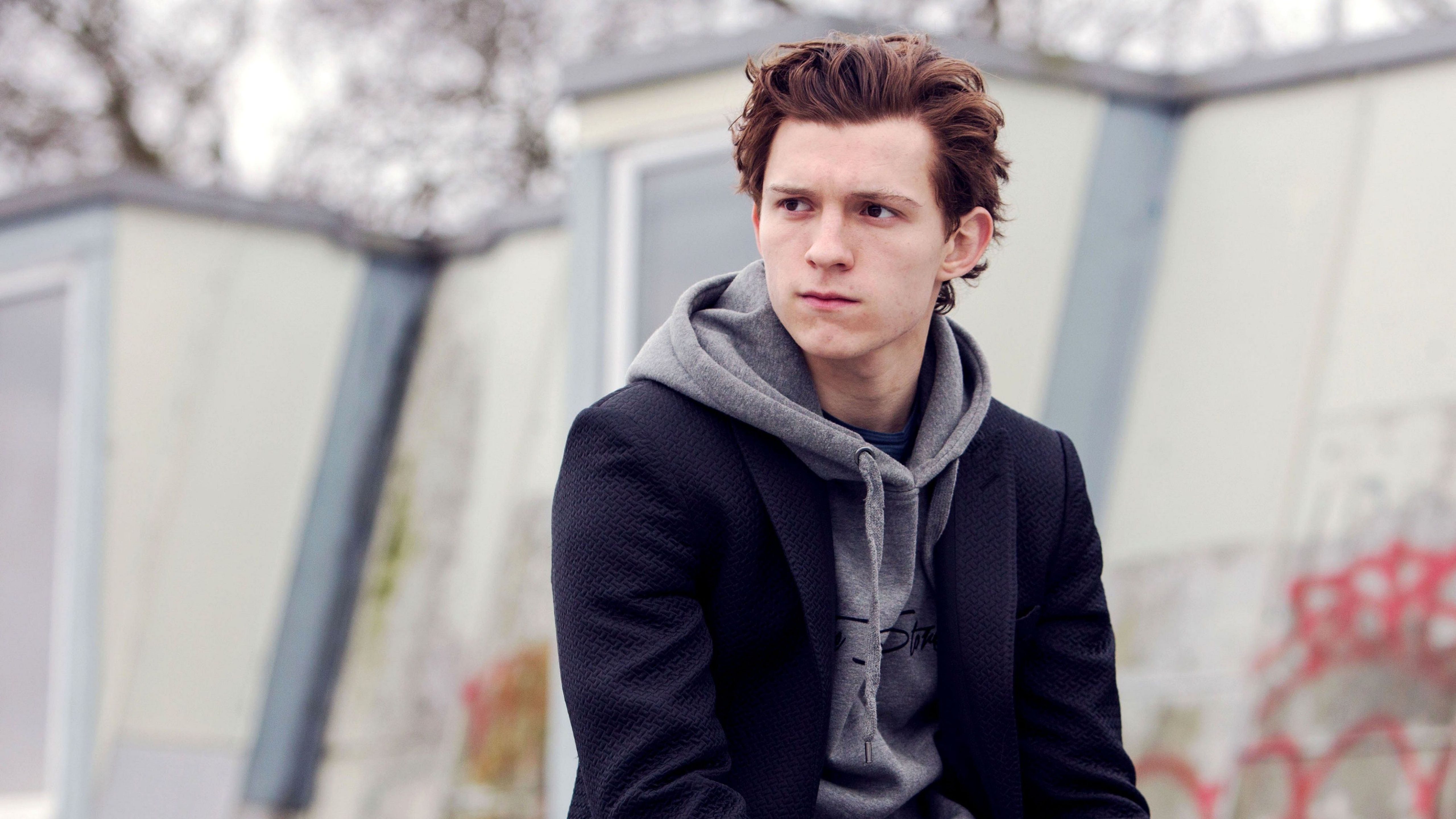 Tom Holland wearing a black jacket and a grey hoodie - Tom Holland