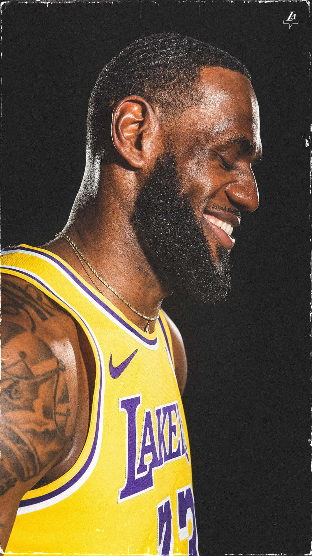 A portrait of LeBron James, smiling and looking to the side, wearing his Lakers jersey. - Lebron James