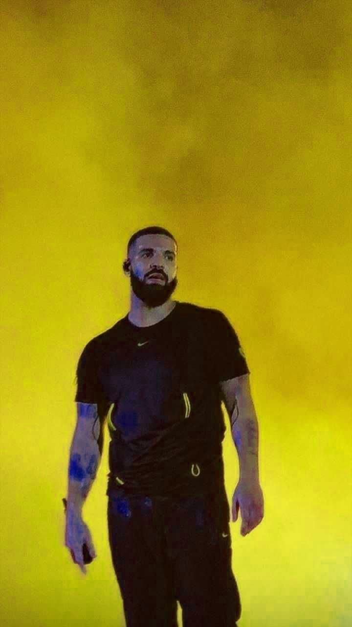 Drake standing in front of a yellow background - Drake