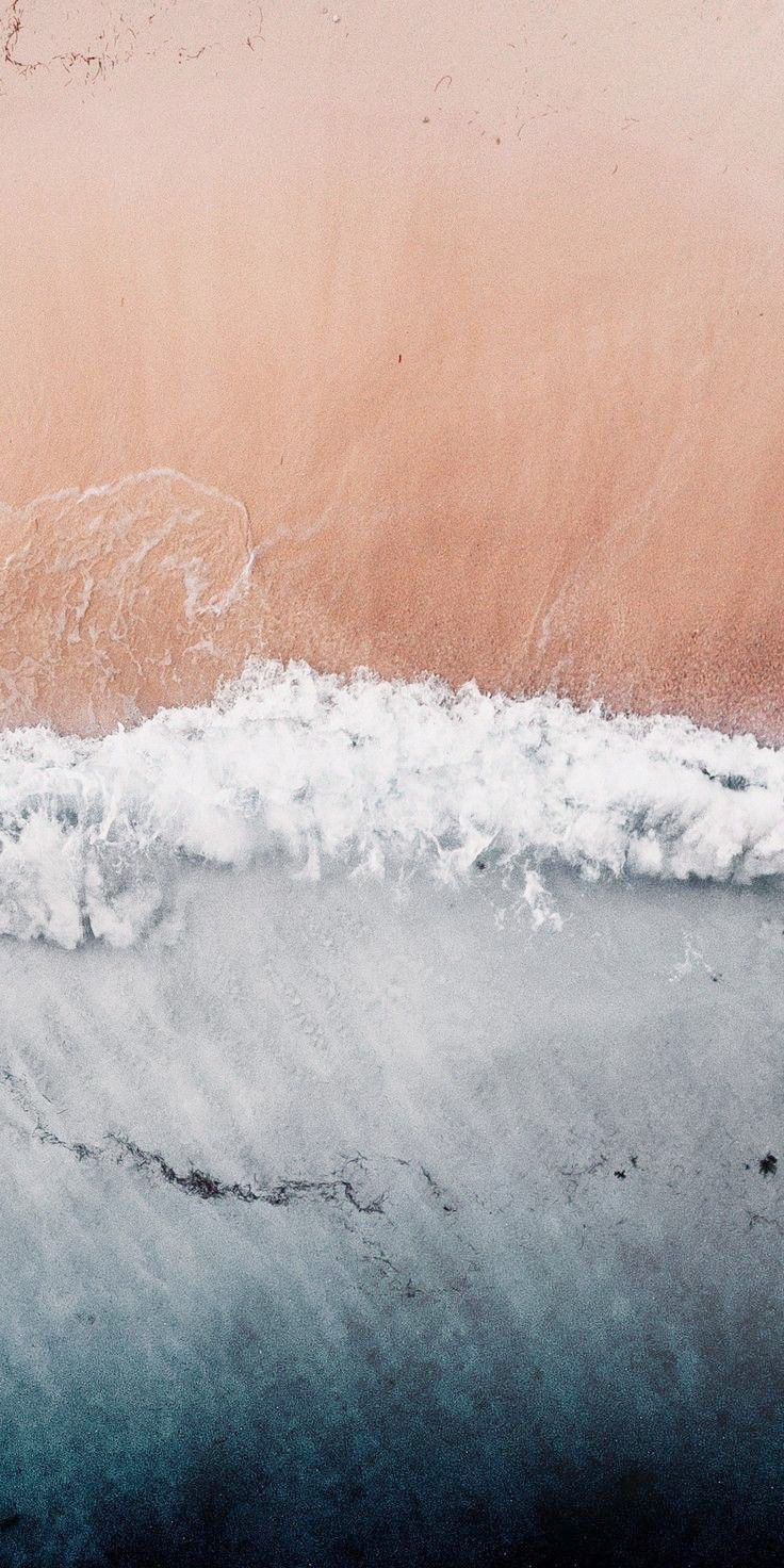 An iPhone wallpaper of a sandy beach with a blue and white wave crashing on it. - Sand