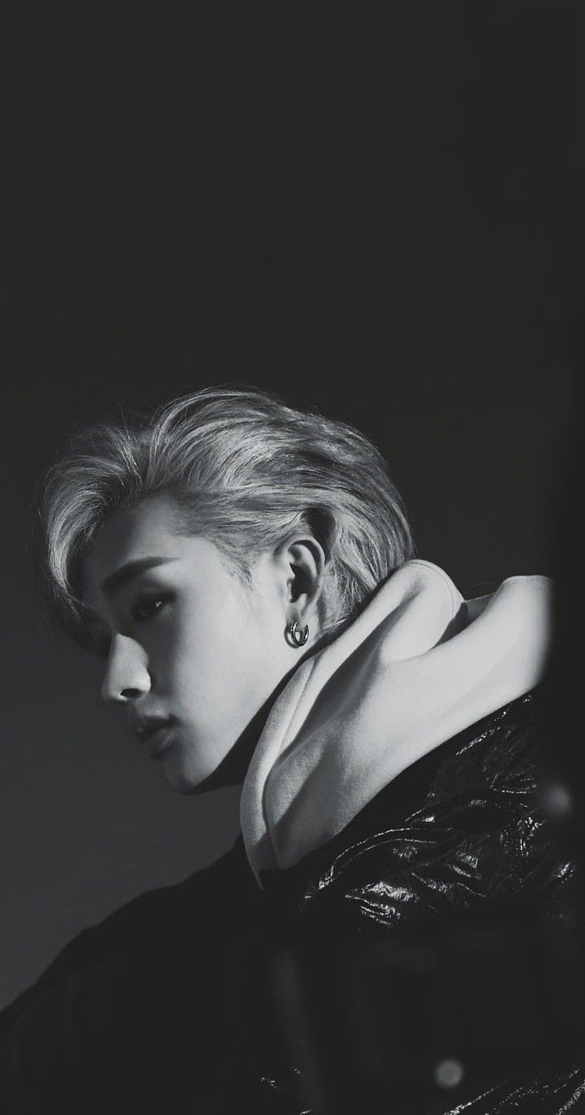 Black and white image of a male model with blonde hair and piercings wearing a black shirt - Bang Chan