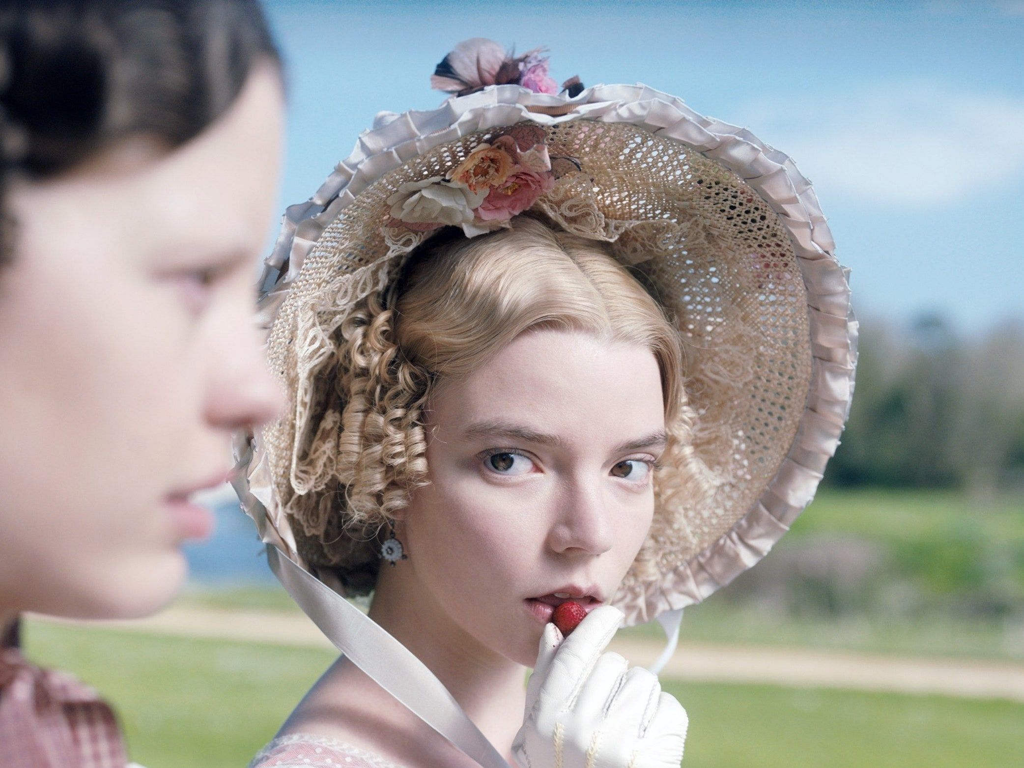 Mia Wasikowska as Jane Eyre, wearing a bonnet and holding a strawberry to her mouth - Anya Taylor-Joy