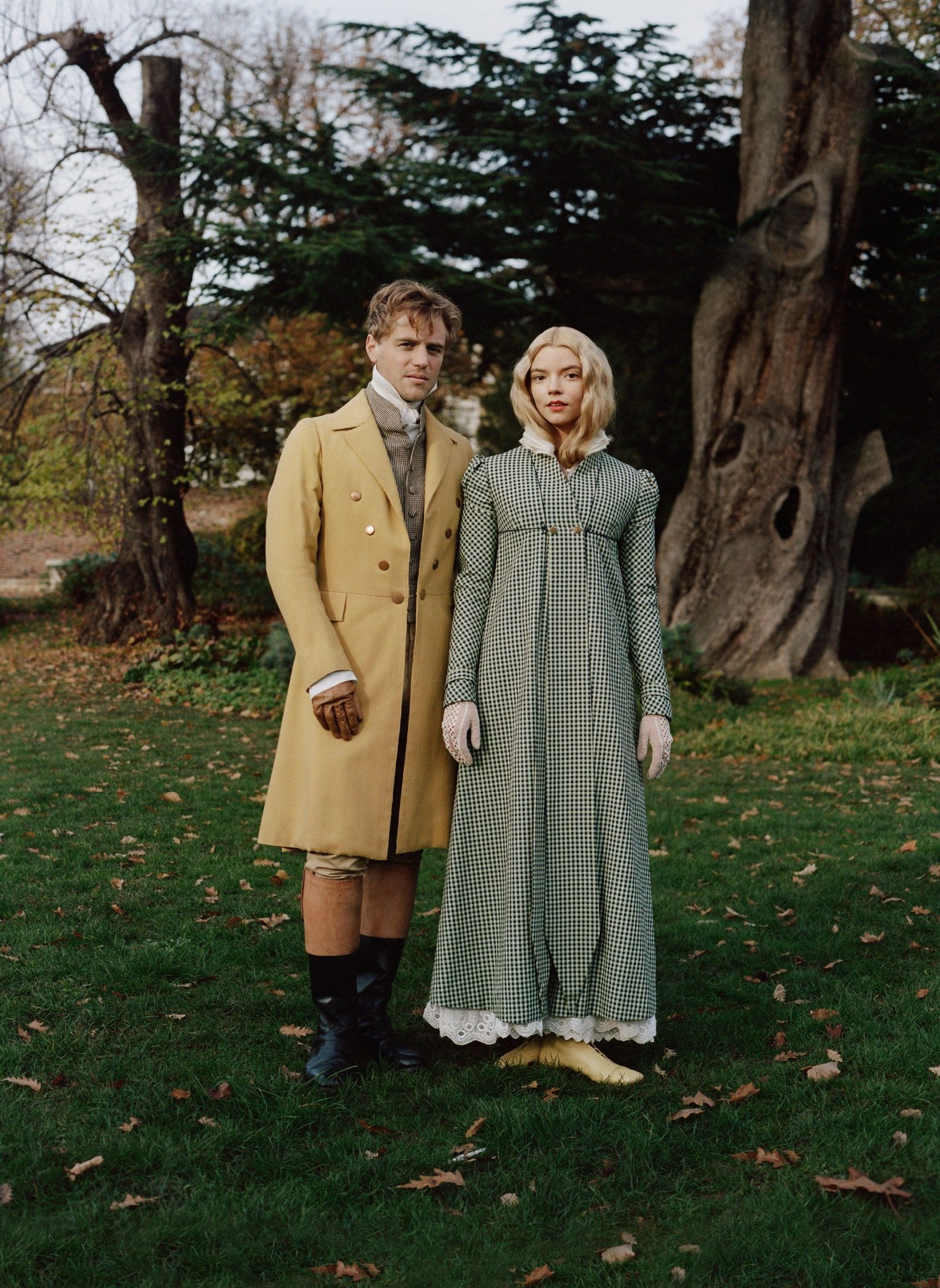 A man and woman stand in a park, dressed in early 20th century clothing. - Anya Taylor-Joy