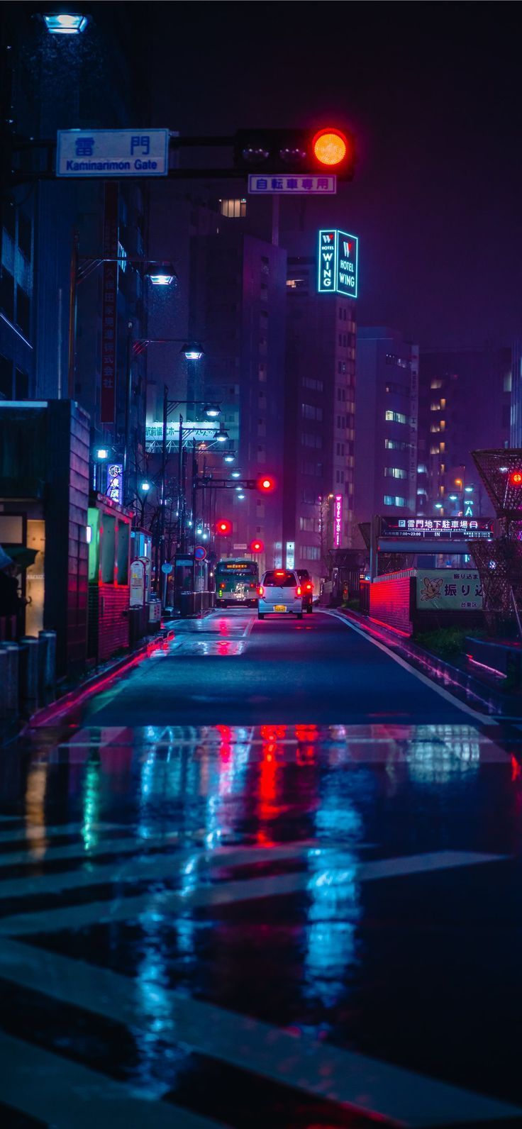 A city street at night with neon lights and rain. - Tokyo