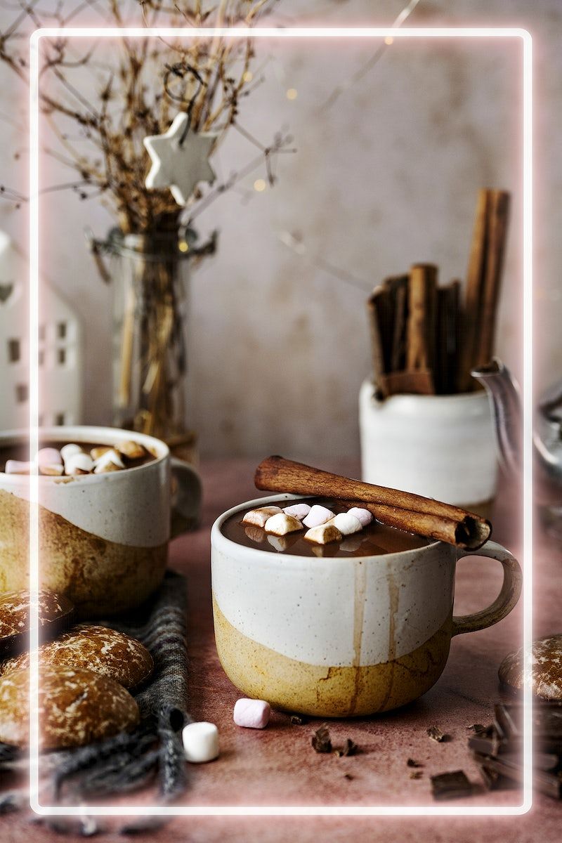A cup of hot chocolate with marshmallows and cinnamon sticks. - Marshmallows