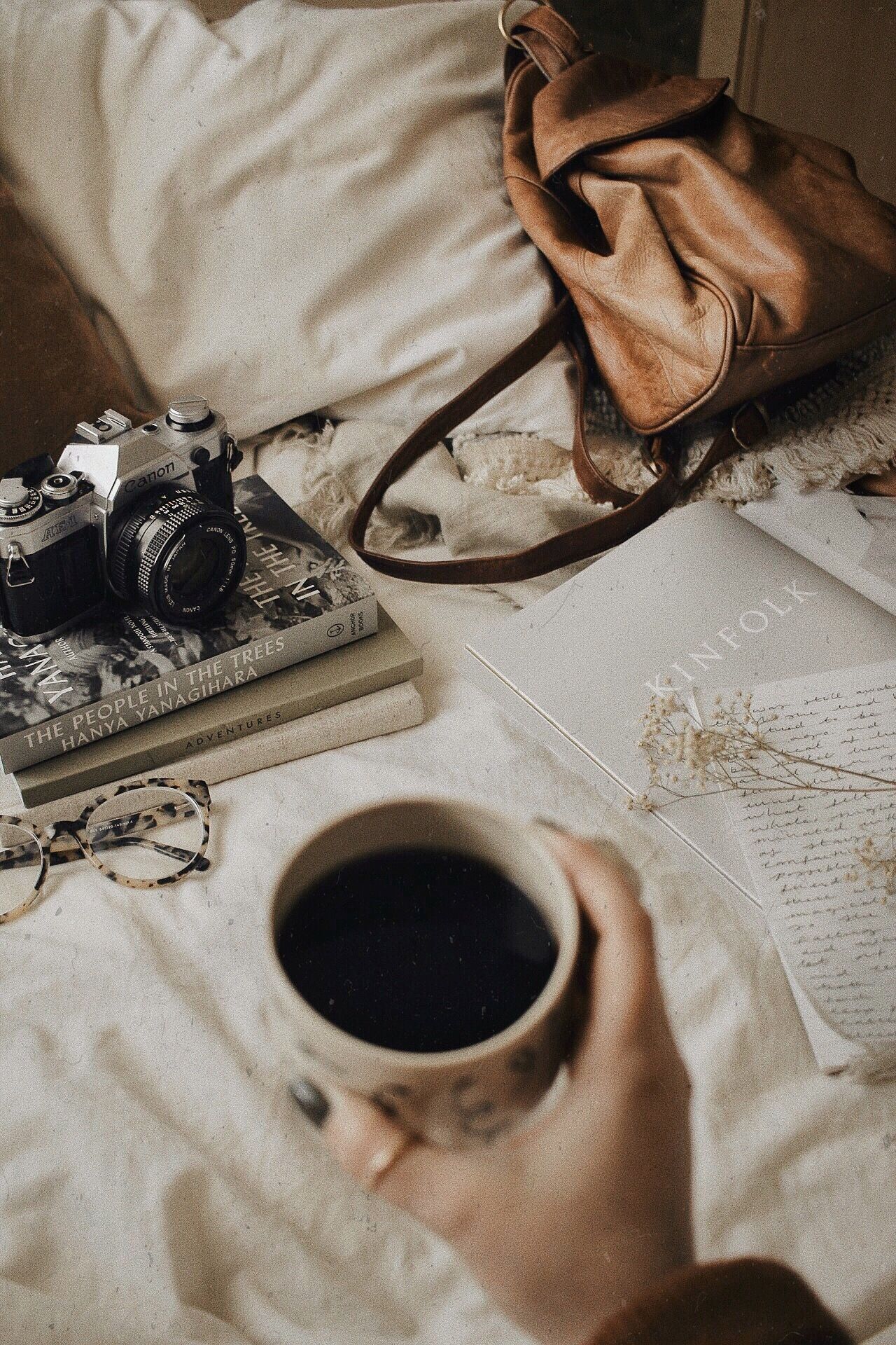 A cup of coffee on a bed with books and a camera - Balance