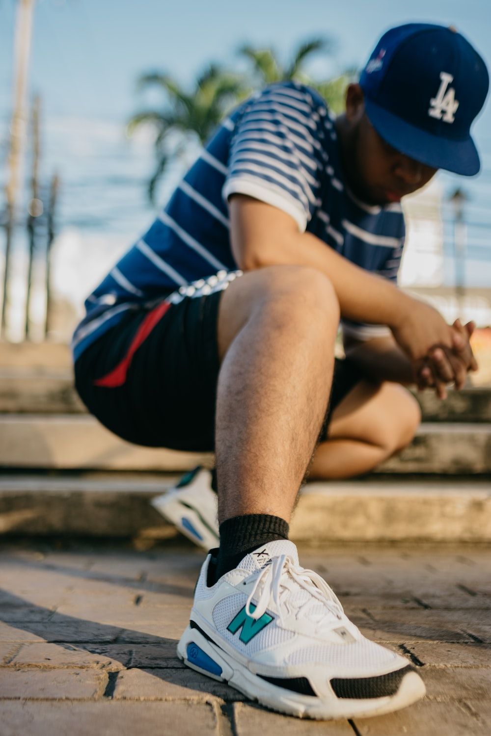 A man sitting on steps tying his shoe - New Balance