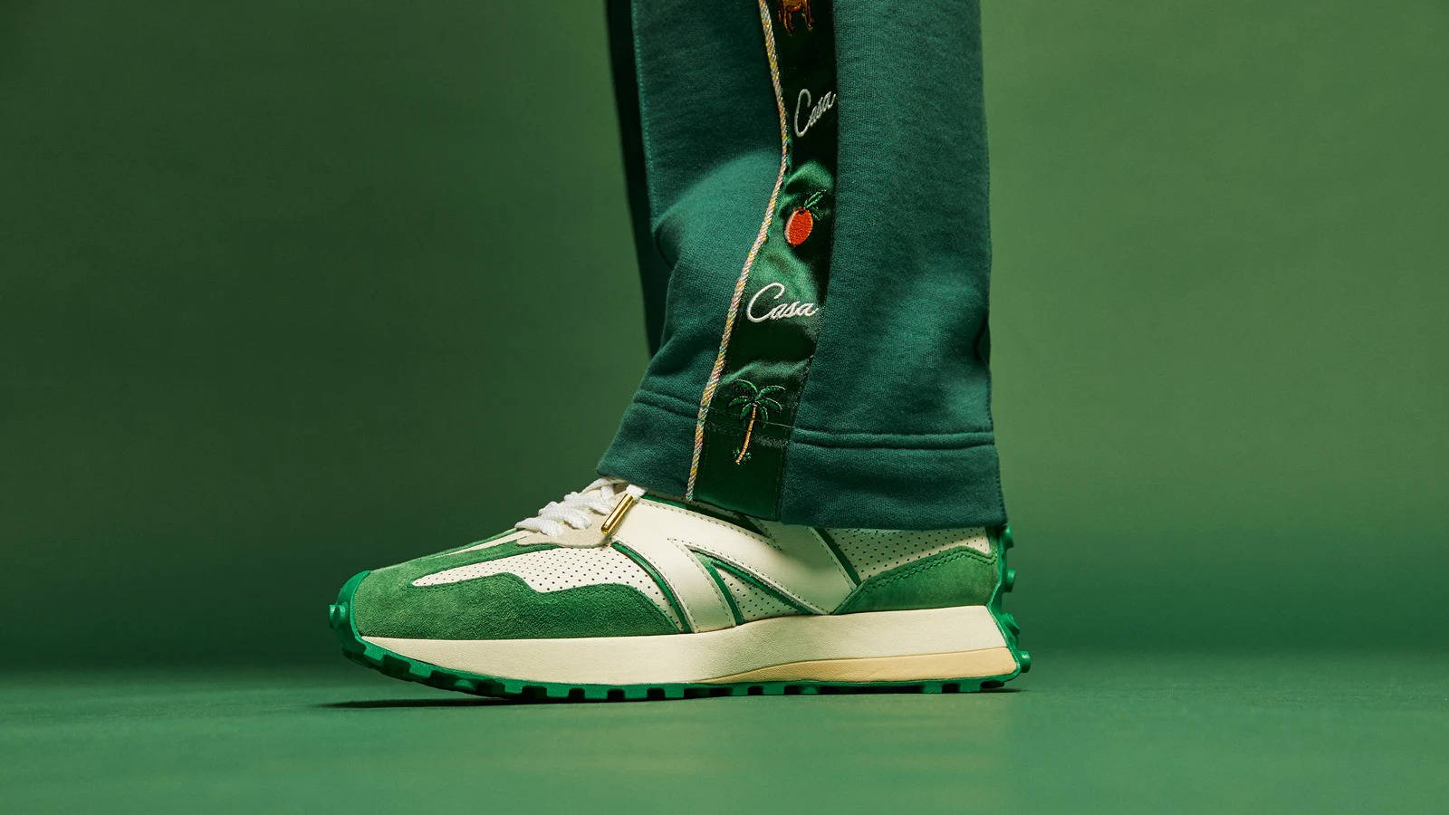 A model wearing green pants and green and white sneakers - New Balance