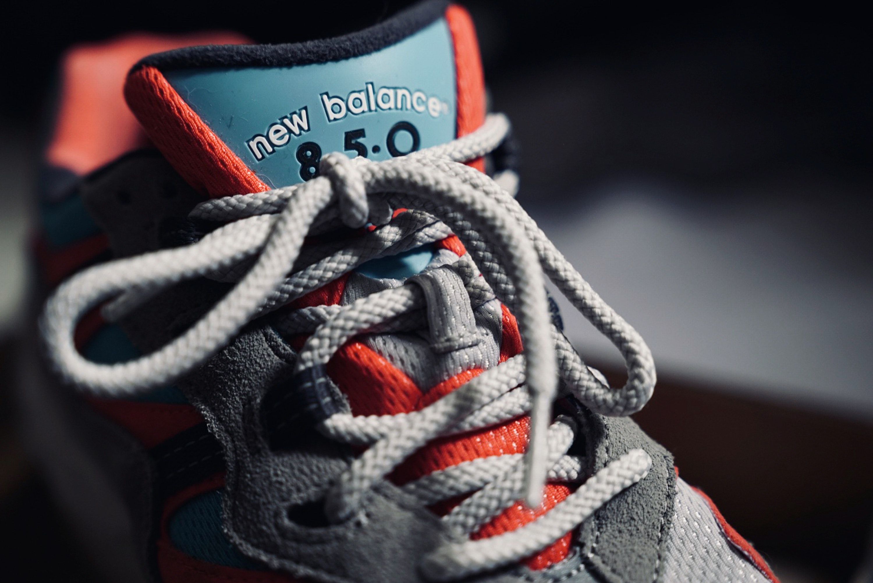 A close up of the laces on a grey and orange New Balance 850 shoe. - New Balance