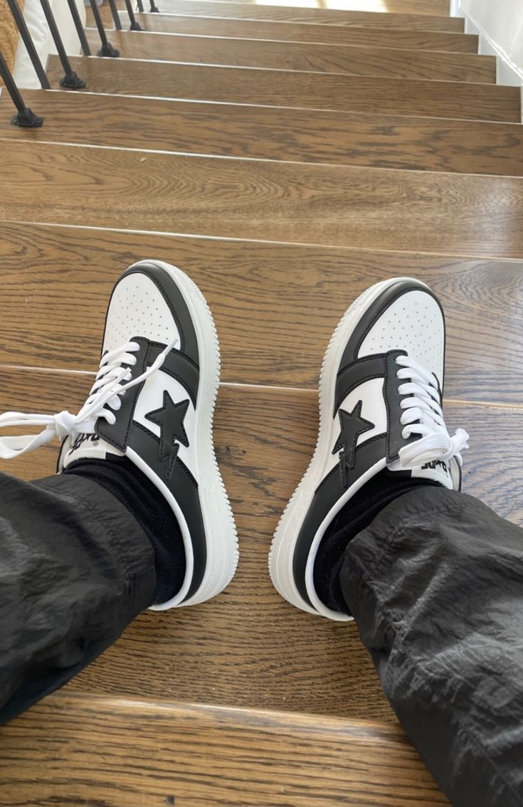 A pair of feet wearing black and white Nike sneakers on a staircase - New Balance