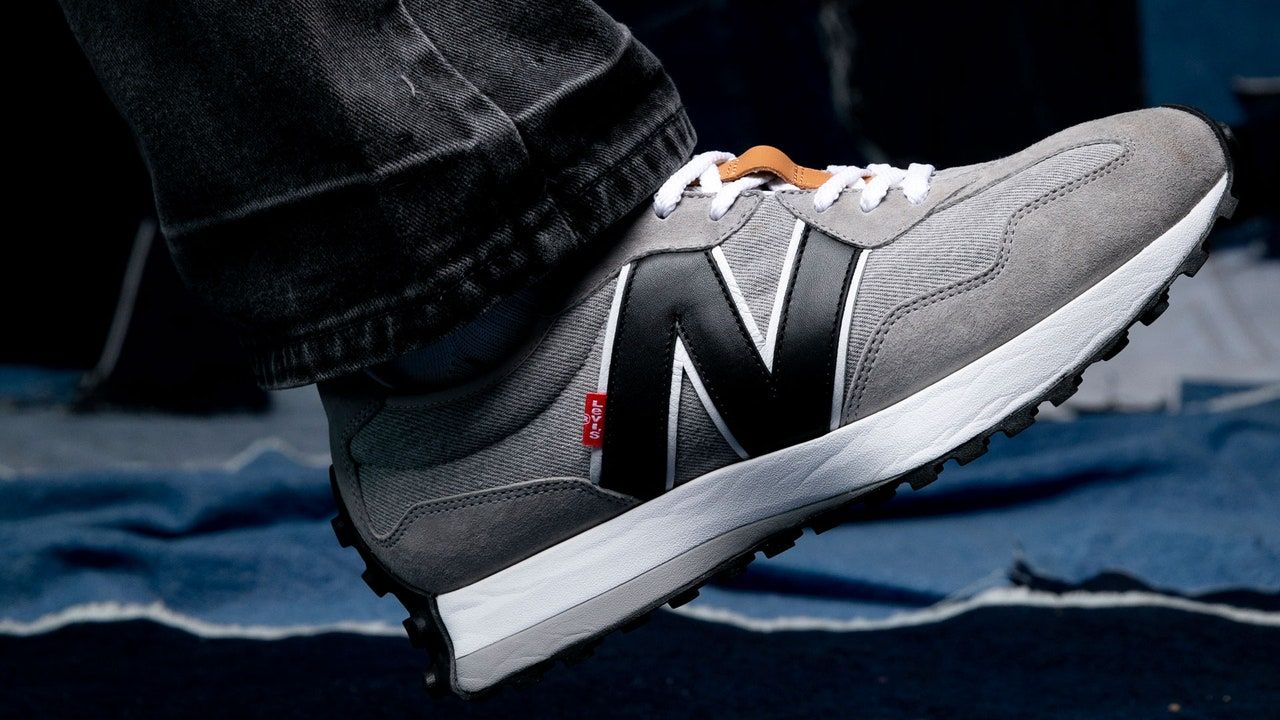 A close up of a person wearing grey new balance sneakers - New Balance