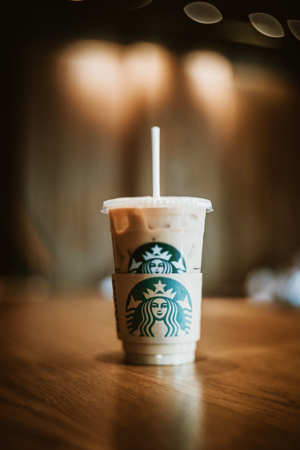 A Starbucks cup with a straw sitting on a table. - Starbucks