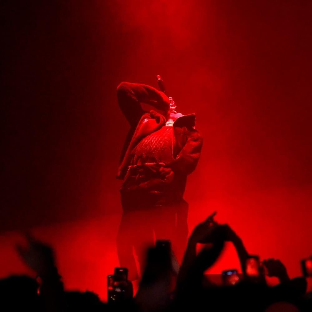 A man standing on stage in front of a crowd. - Kanye West