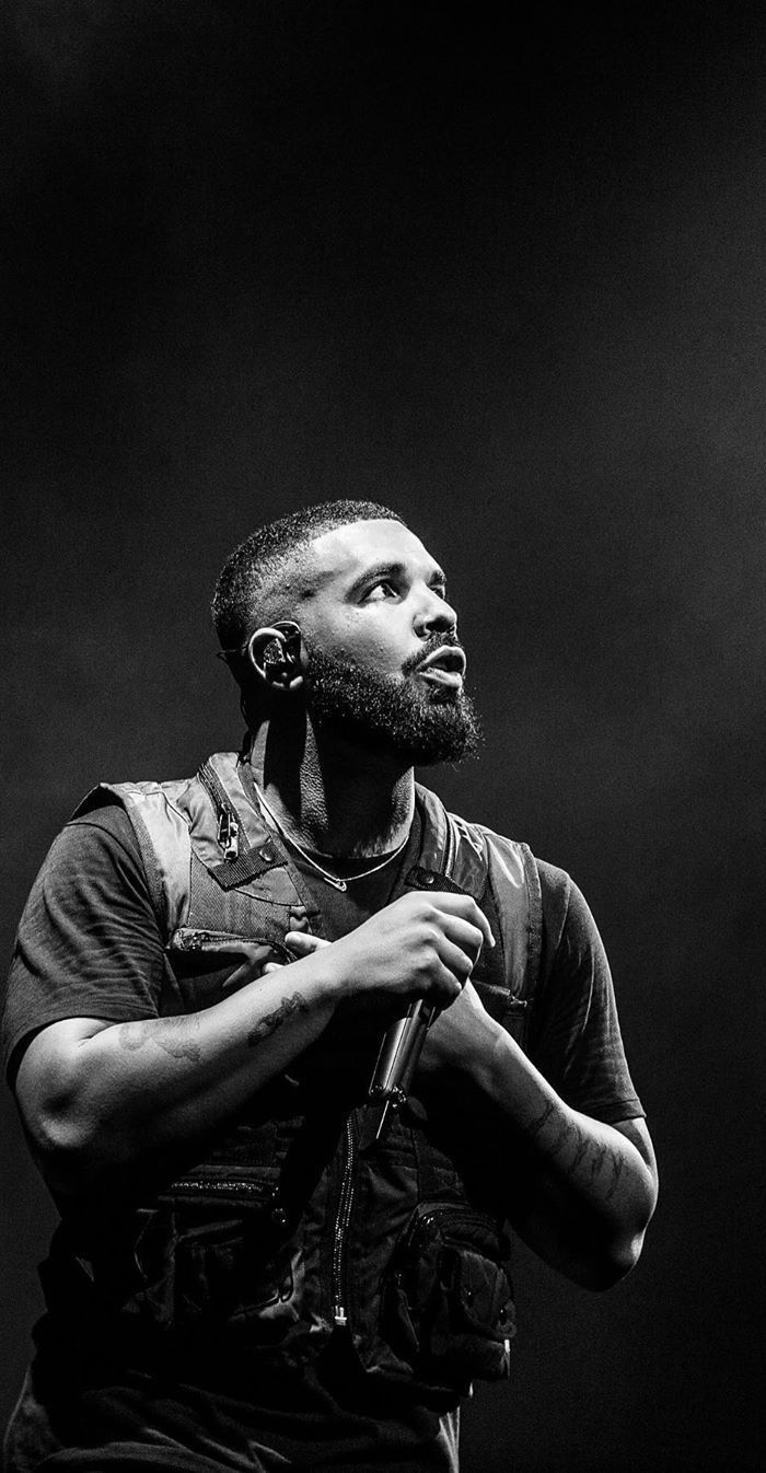 A black and white photo of a man holding a microphone. - Drake