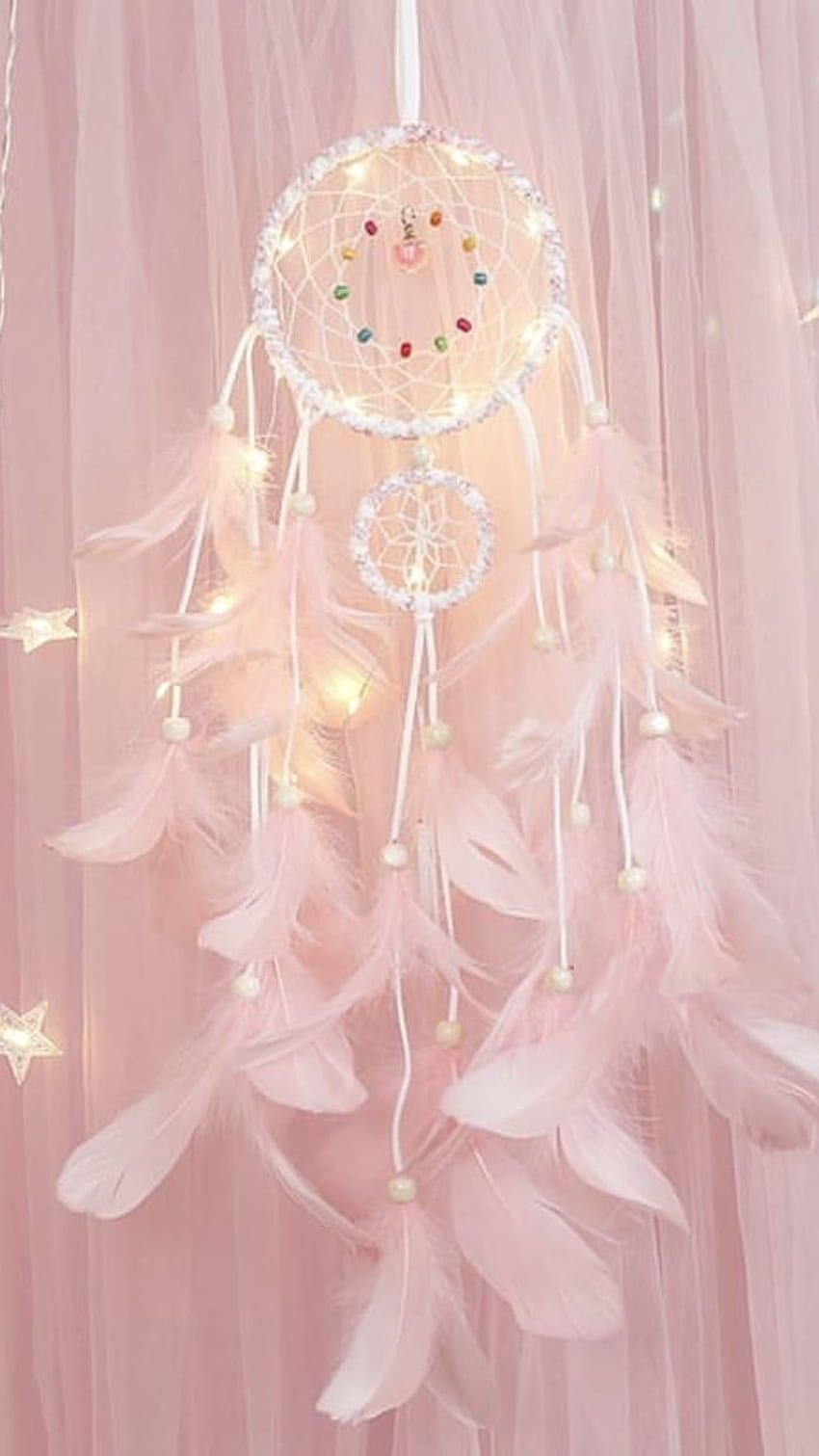 A pink dream catcher with white LED lights and feathers. - Blush