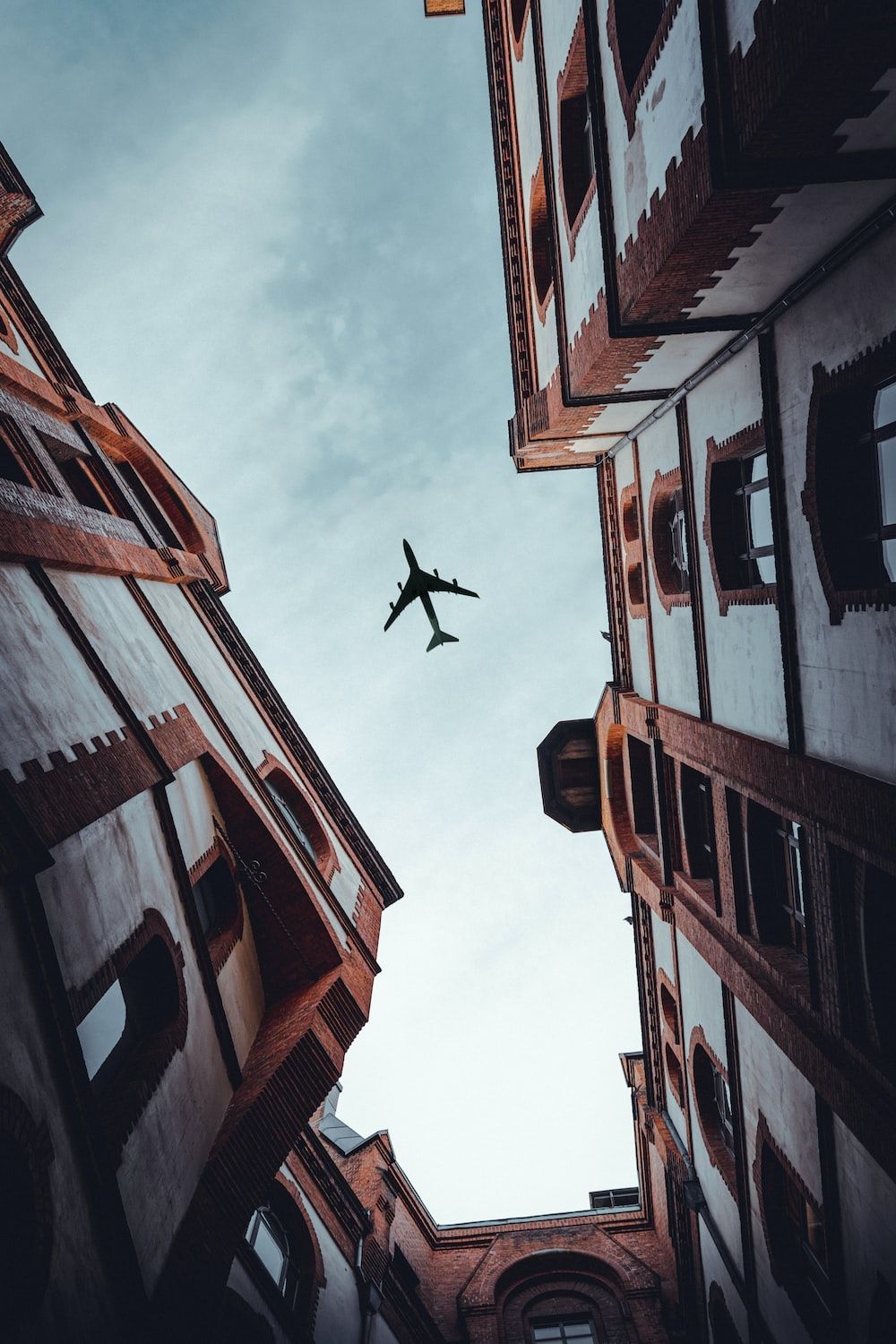 A plane flying over white buildings. - Airplane