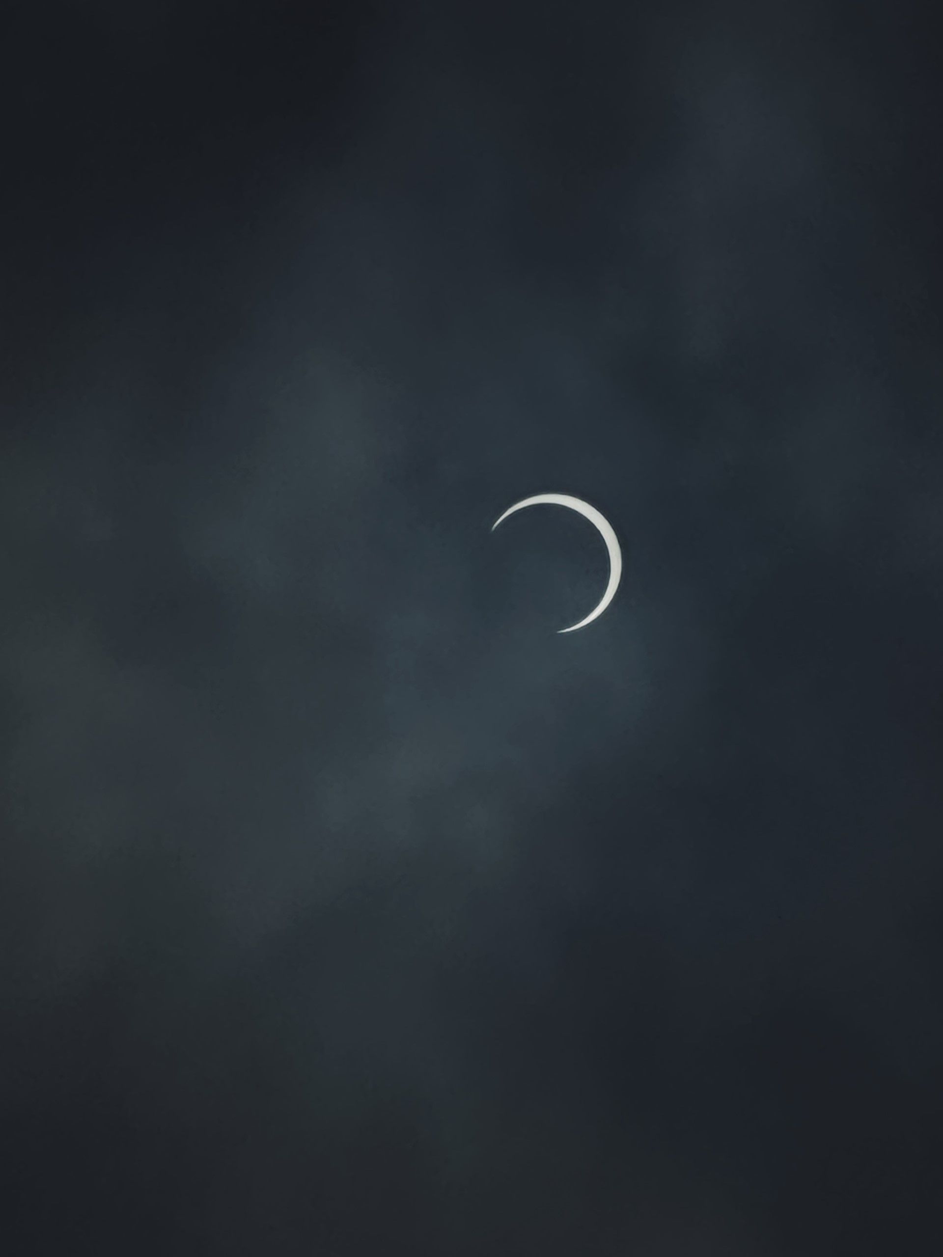 A partially eclipsed sun, with a thin crescent of the moon visible in a dark sky. - Eclipse