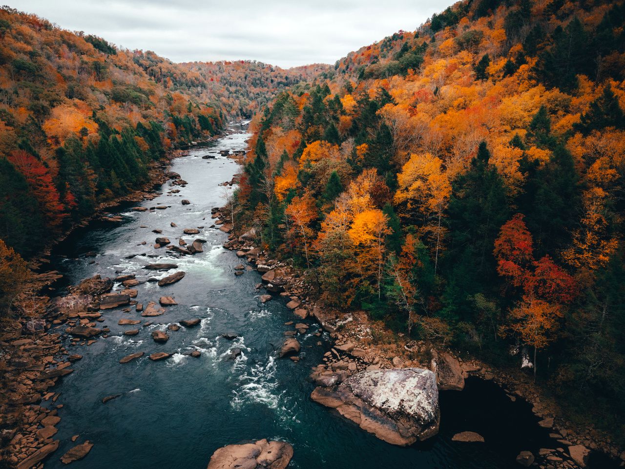 A river surrounded by trees with fall foliage - River