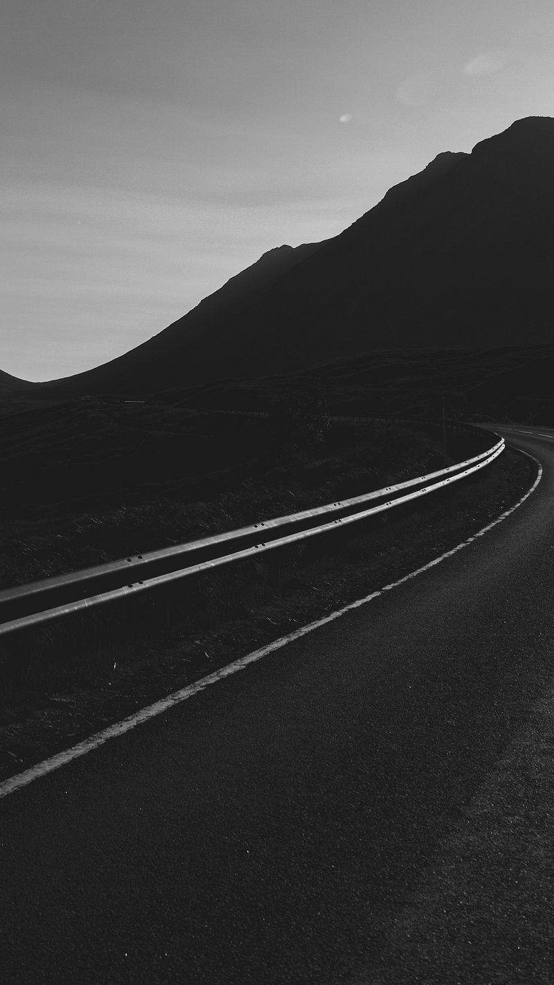 A black and white photo of a road with a mountain in the background - Black phone