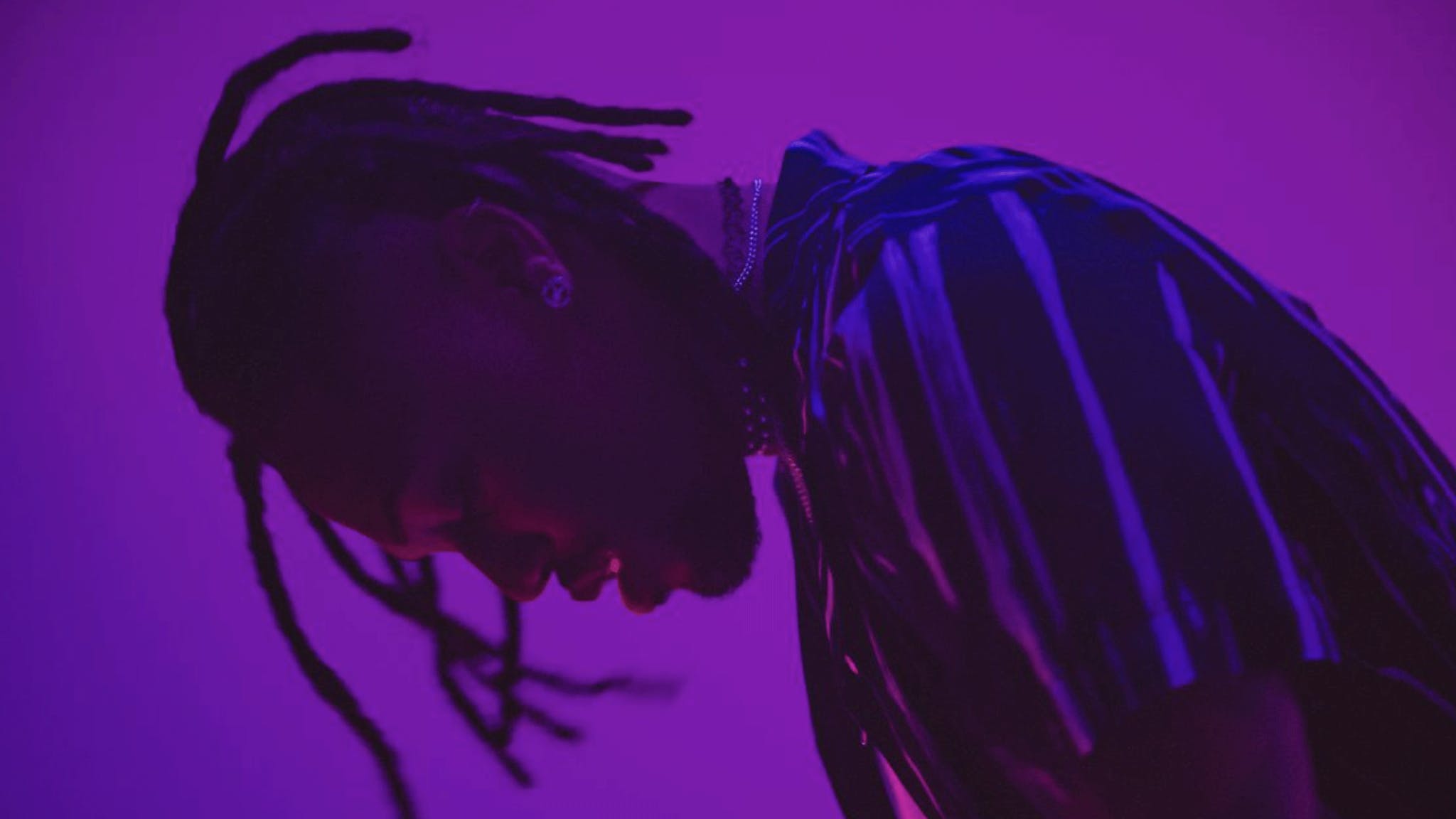 Travis Scott wearing a black and white striped shirt in front of a purple background - 2048x1152