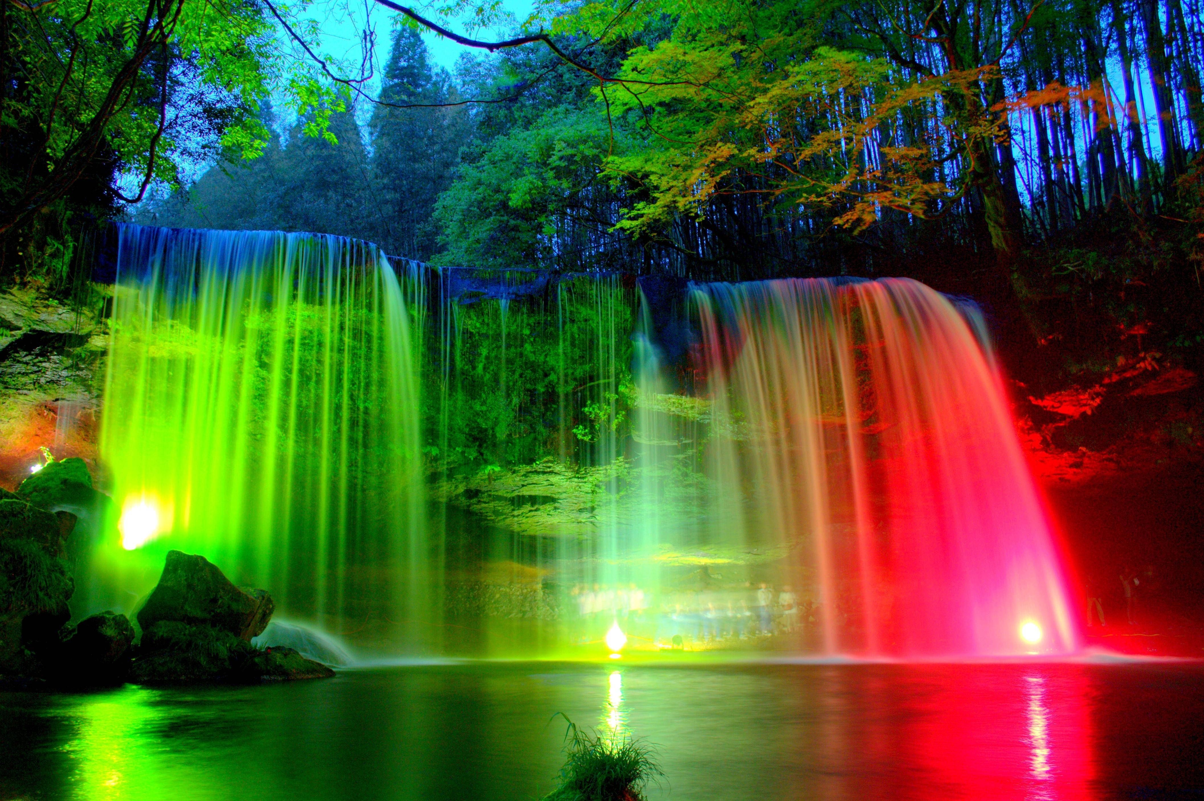 A waterfall is lit up with different colors of light. - Waterfall