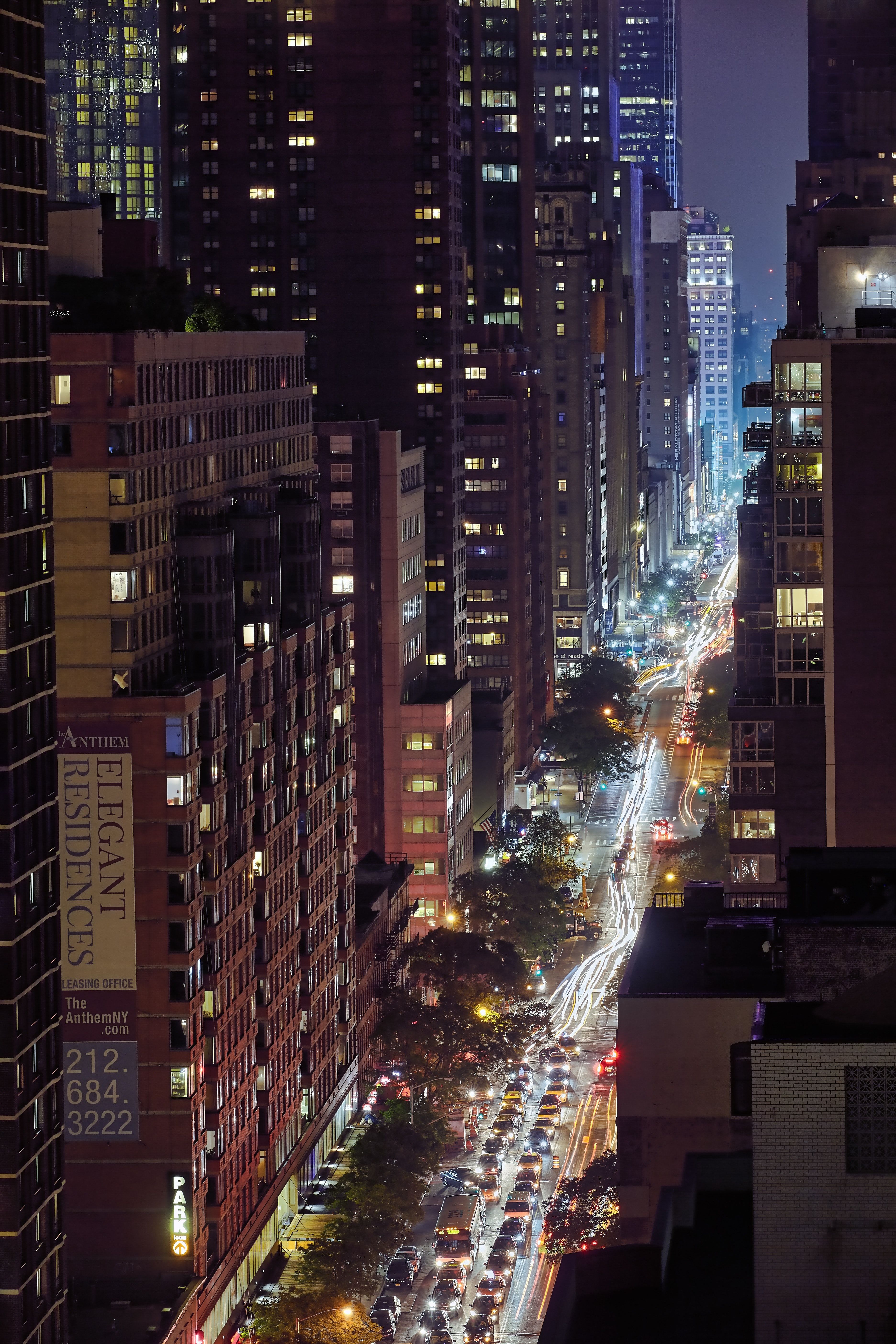 A city street at night with traffic and tall buildings. - New York, skyline