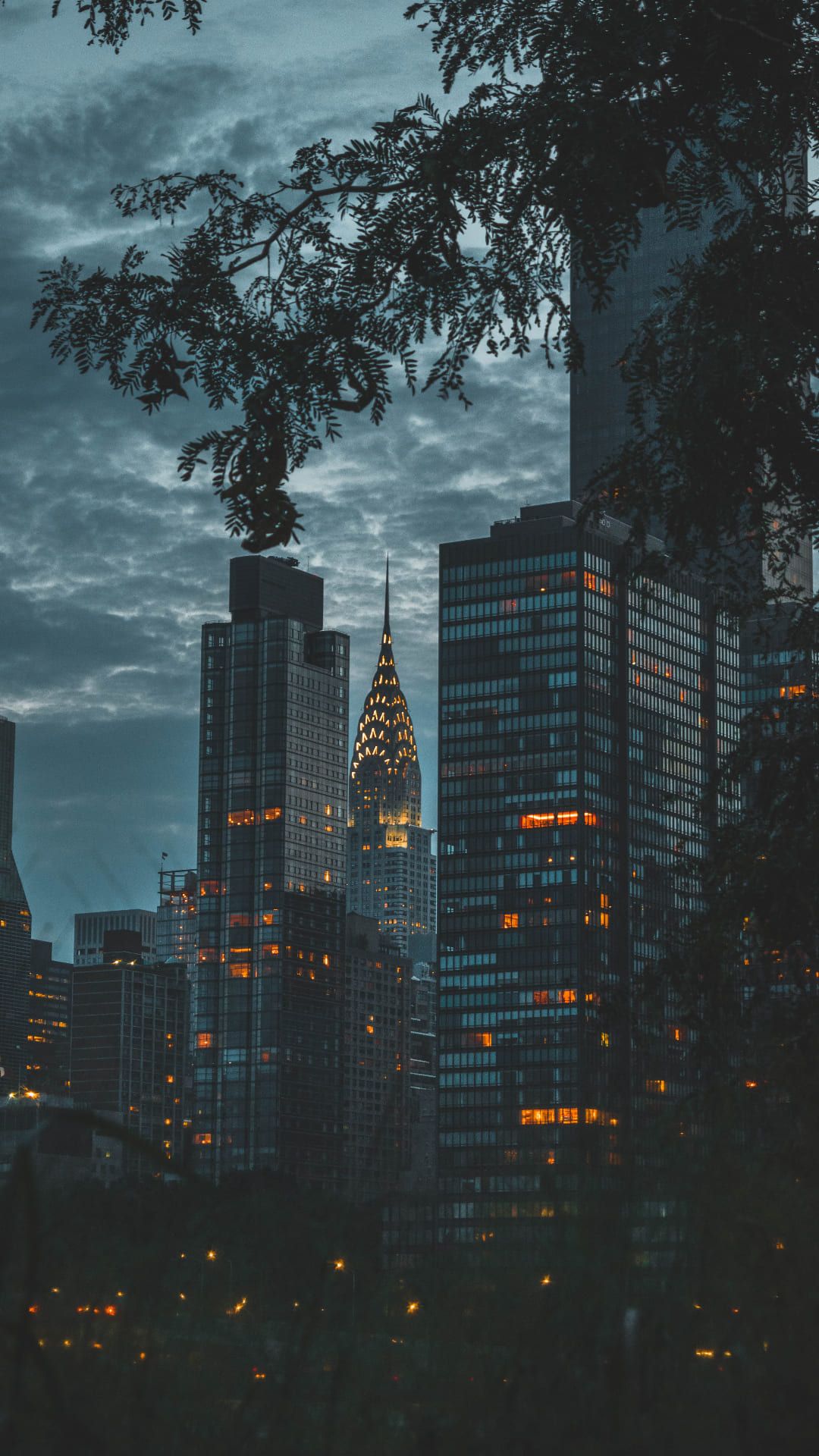 A city skyline at dusk with trees in the foreground - New York