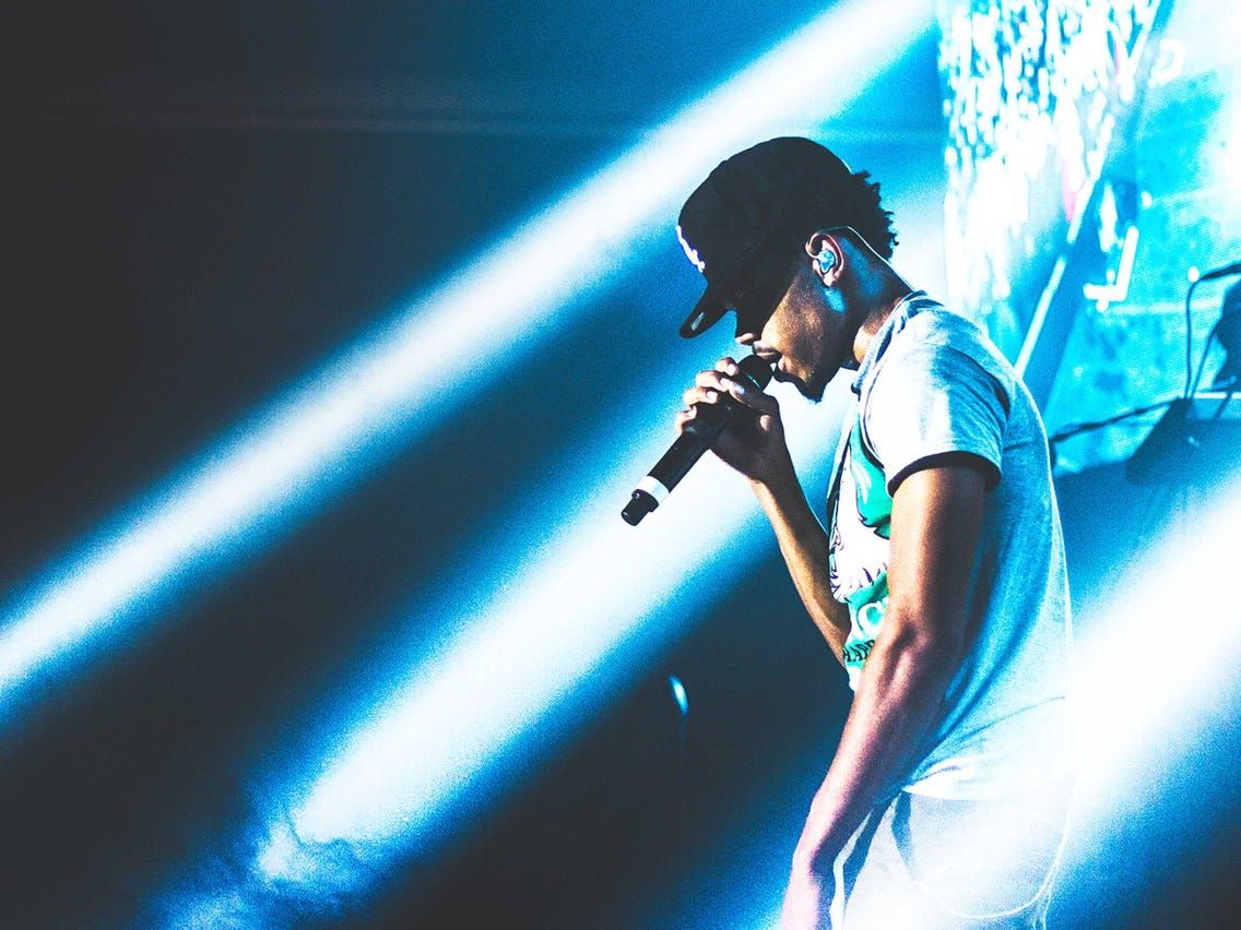 Chance the Rapper performs in a white t-shirt and black baseball cap. - Chance the Rapper