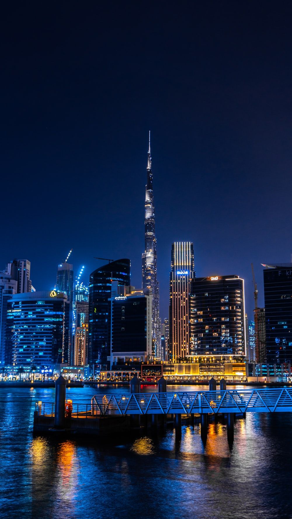 A cityscape at night with the tallest building in the middle - Dubai