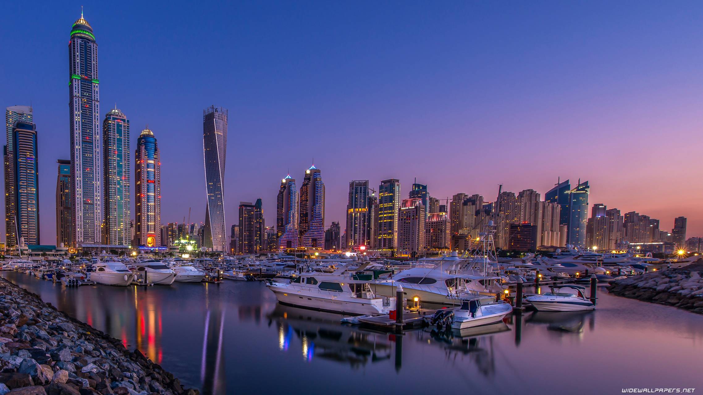The skyline of Dubai at night with boats in the foreground. - Dubai