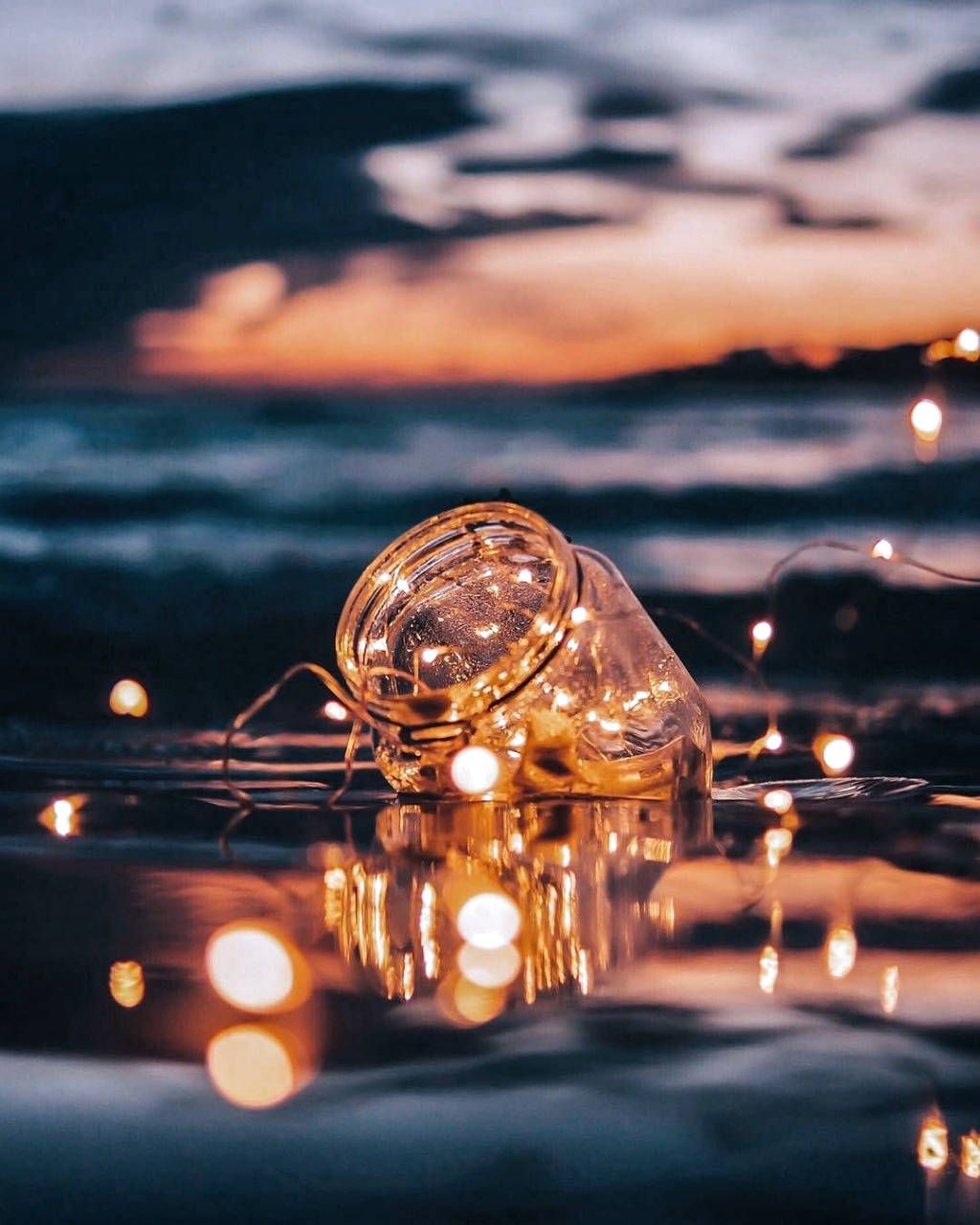 Download A Glass Jar With Lights Floating In The Water Wallpaper