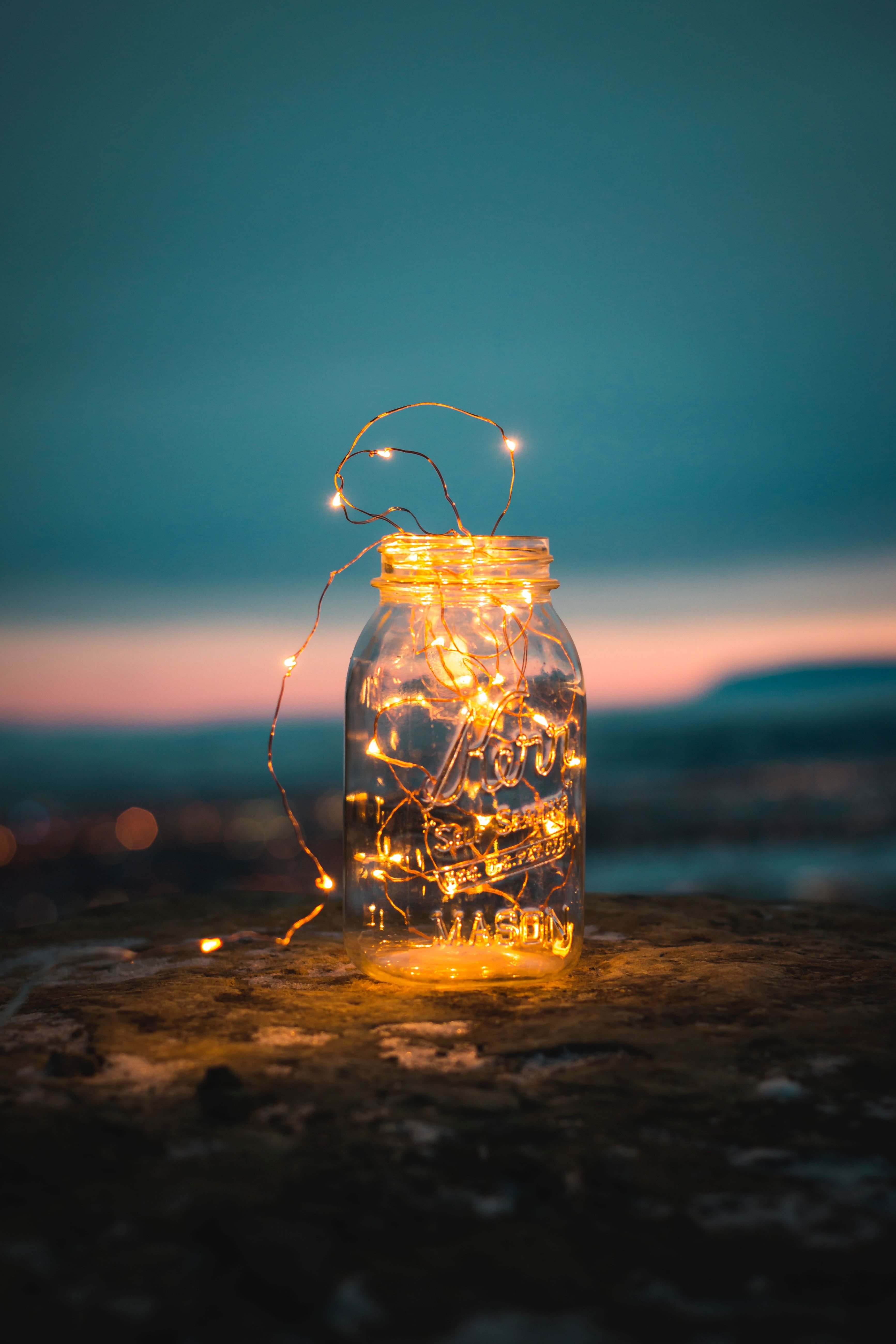 A jar with fairy lights on a rock by the sea - Fairy lights