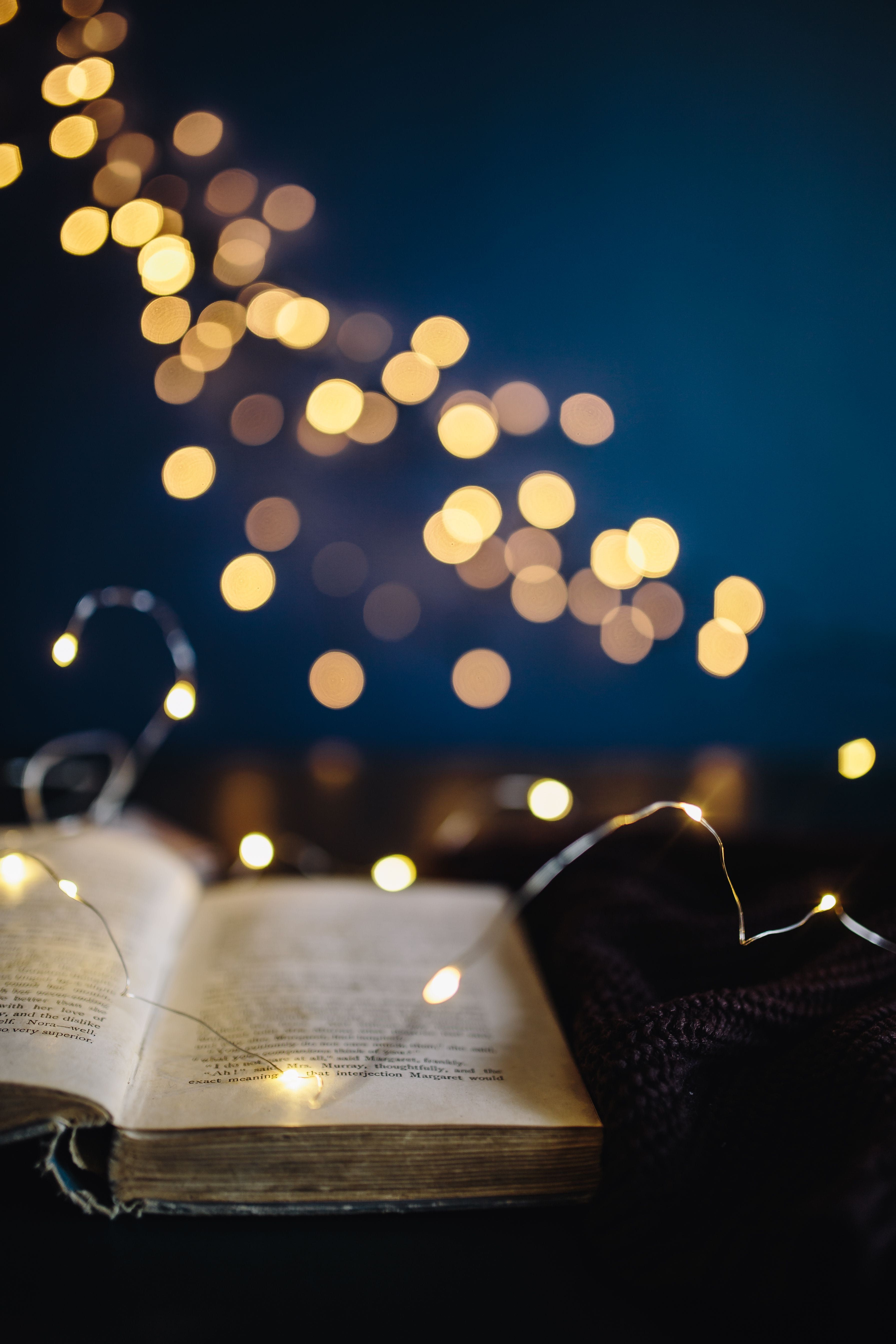 An open book with a lighted string of lights in the background - Fairy lights
