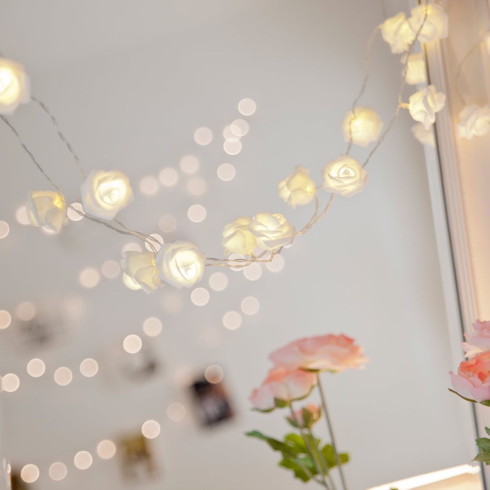 A string of white roses with lights in a room. - Fairy lights