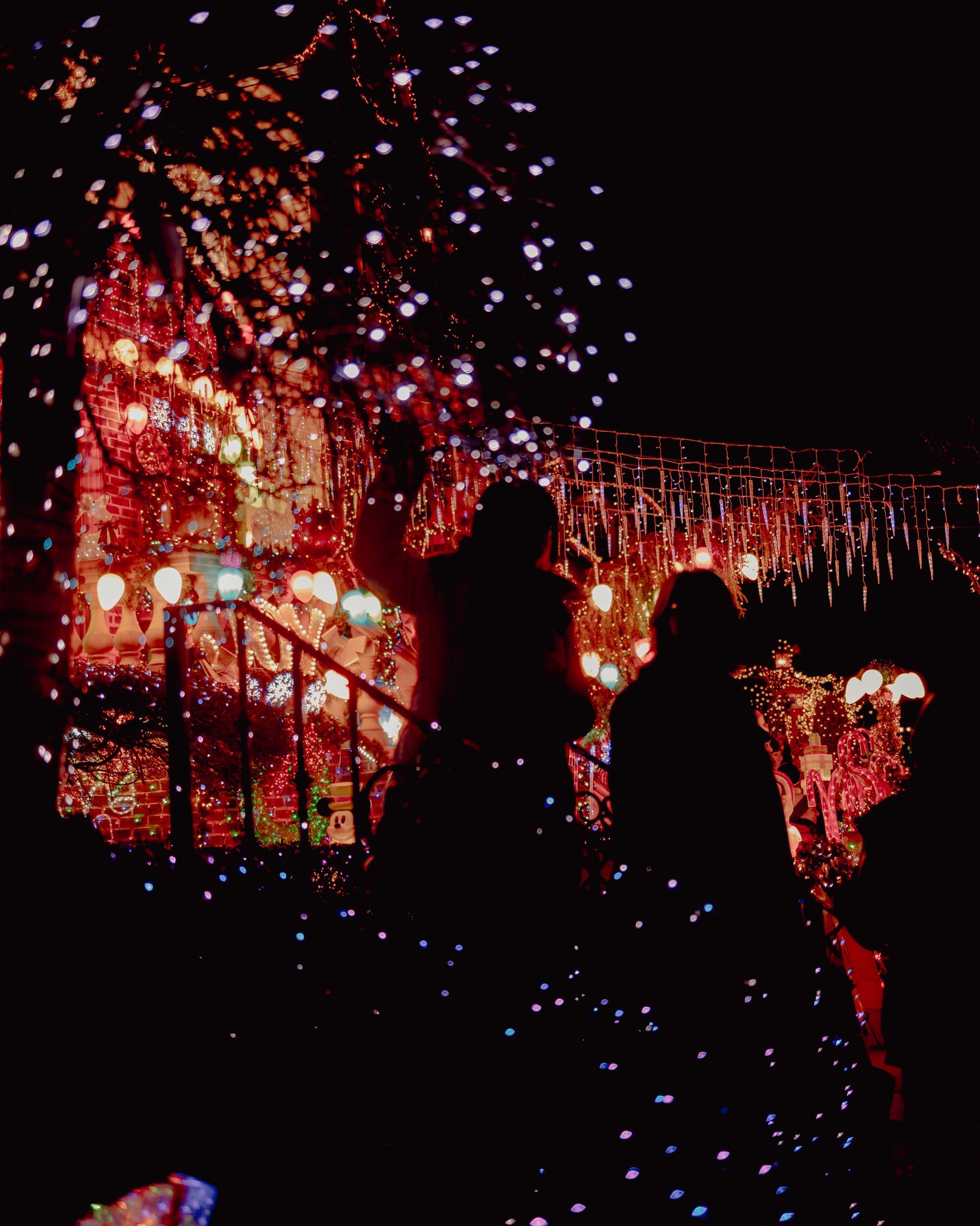 Silhouette of people standing under a string of lights - Fairy lights