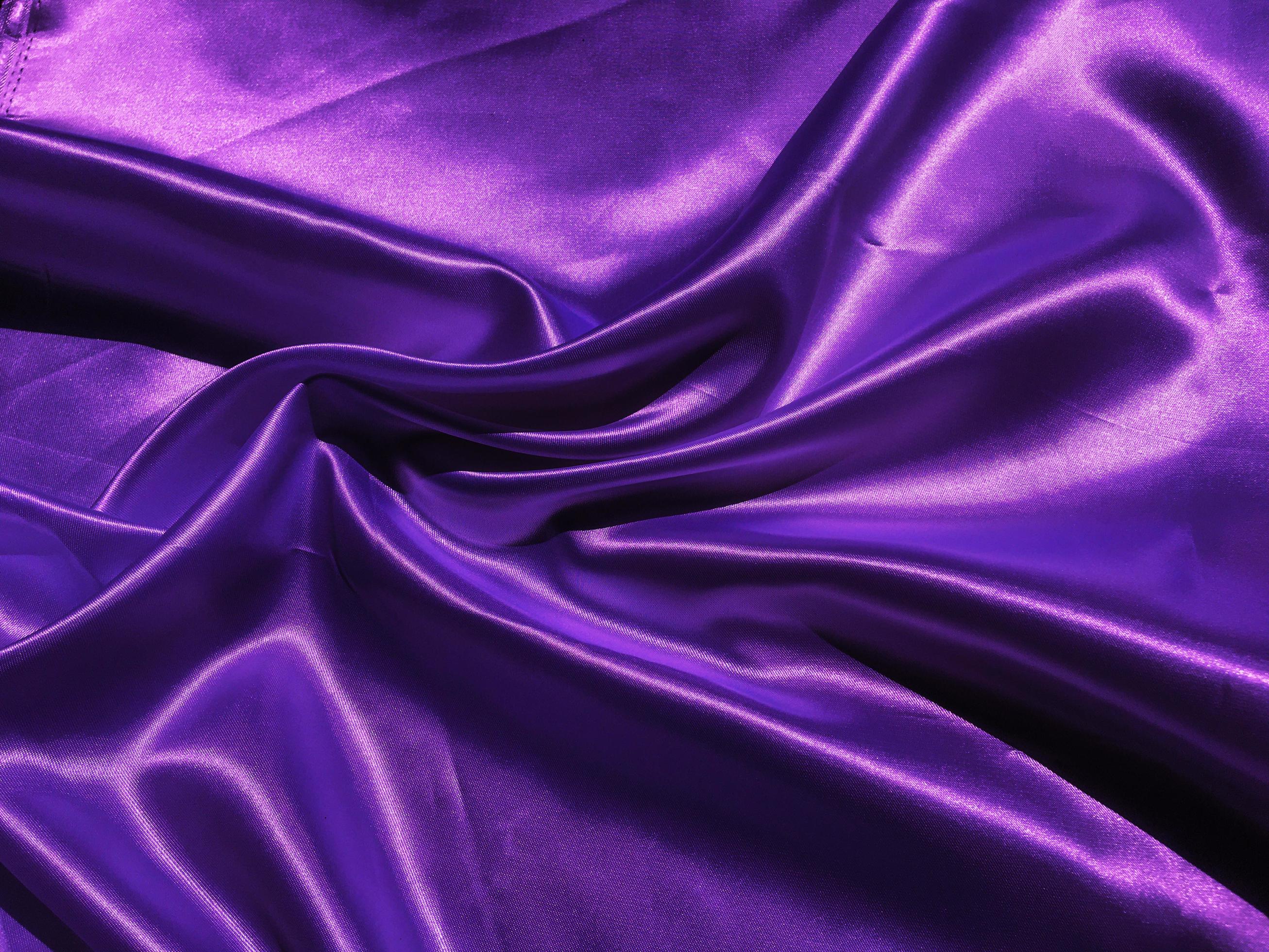 Closeup of purple satin or silk texture background. Copy space with elegant wallpaper design
