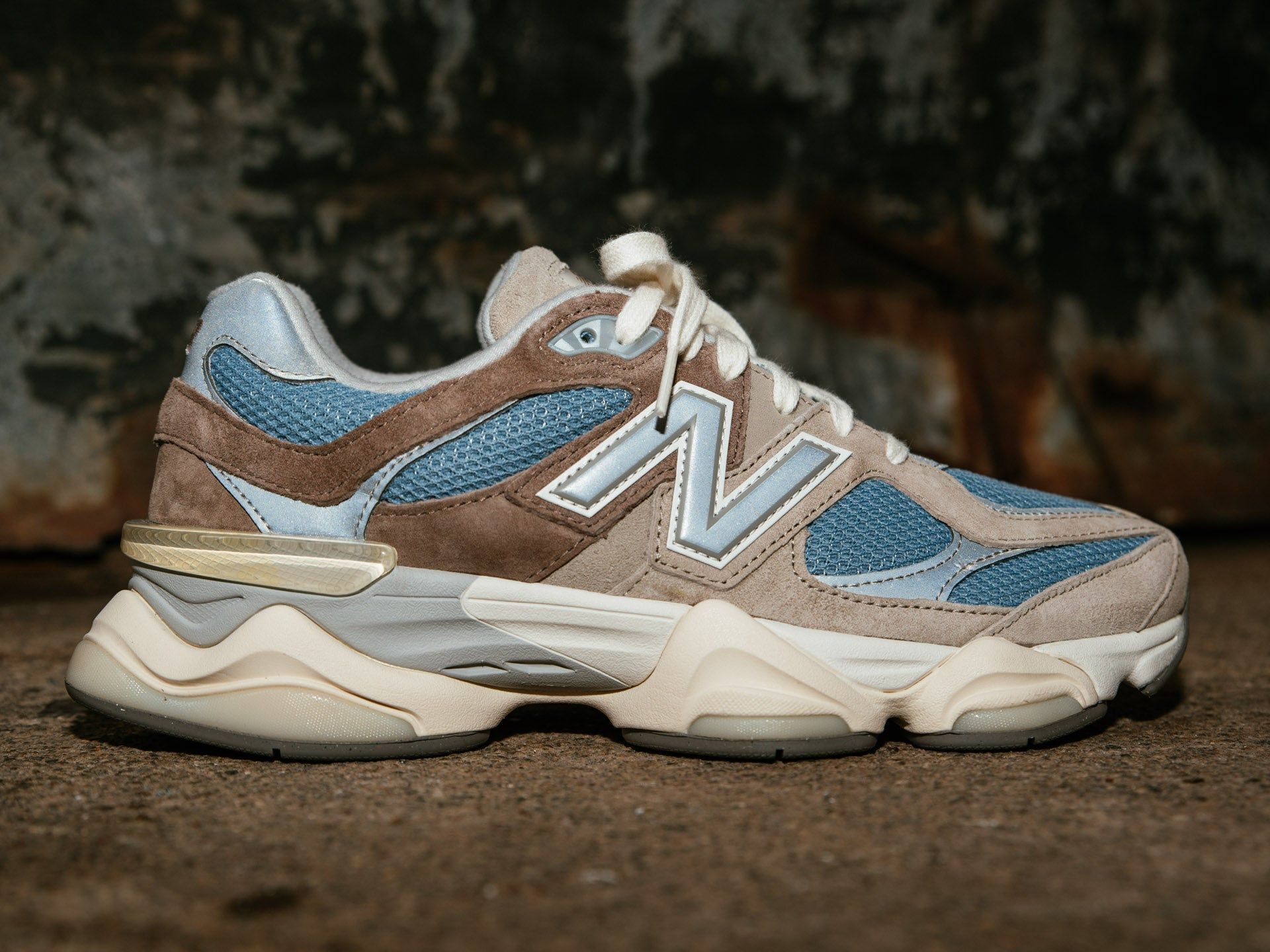 A tan and blue New Balance 990v5 on a stone background - New Balance