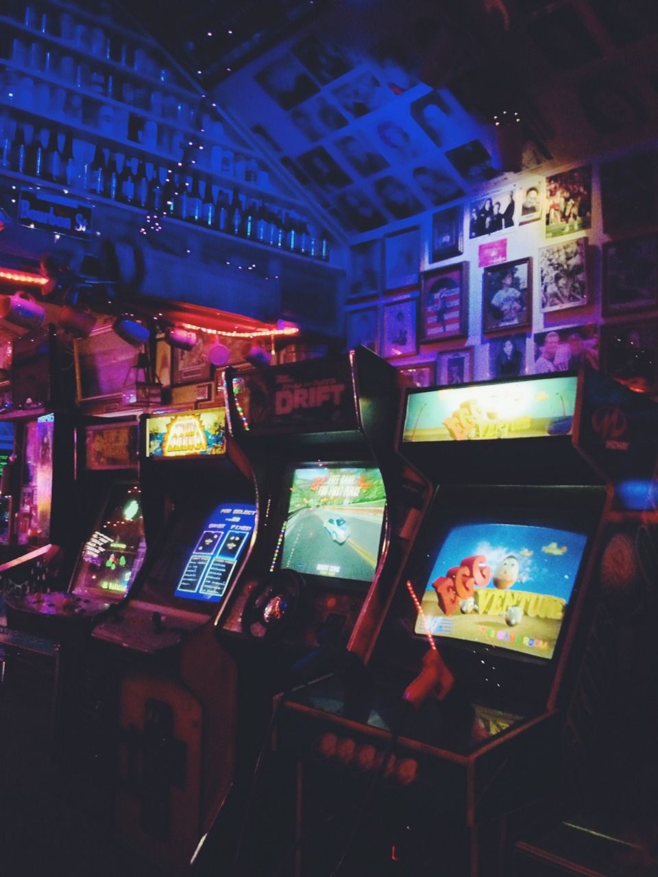 A row of video games lit up in a dark room. - Arcade