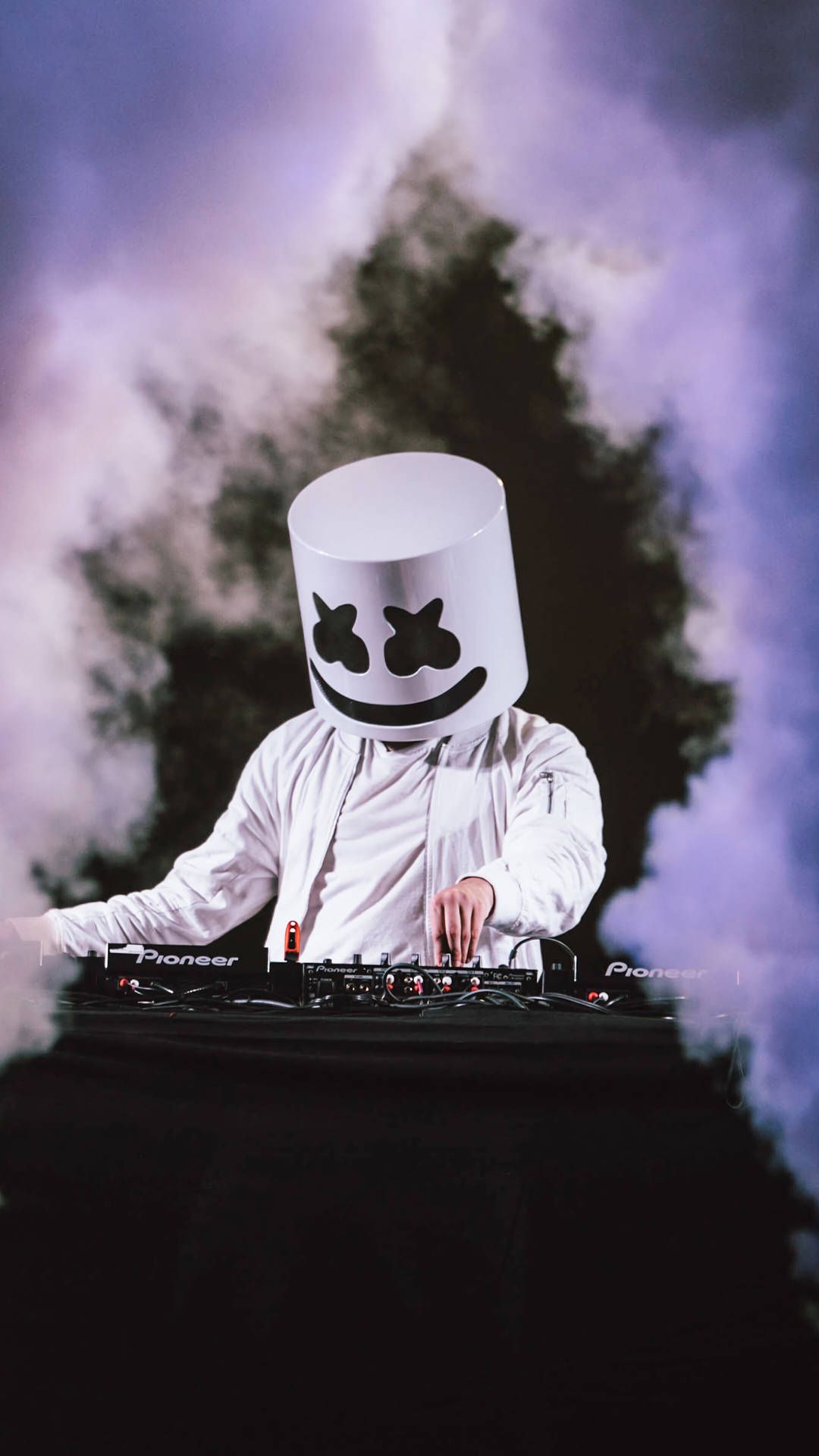 Marshmello in a white shirt mixing music on a Pioneer DJ turntable. - Marshmello