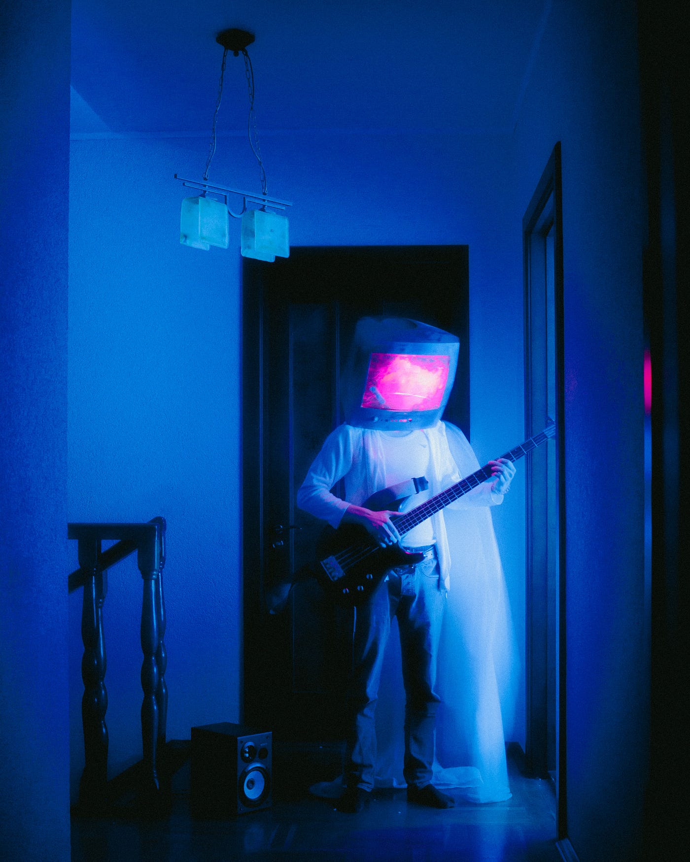 A person wearing a helmet with a screen for a face stands in a blue room holding a guitar. - Marshmello