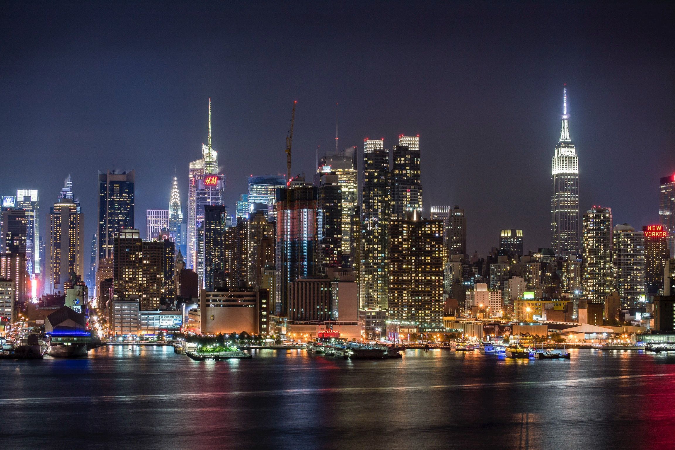 A city skyline at night with boats in the water - New York