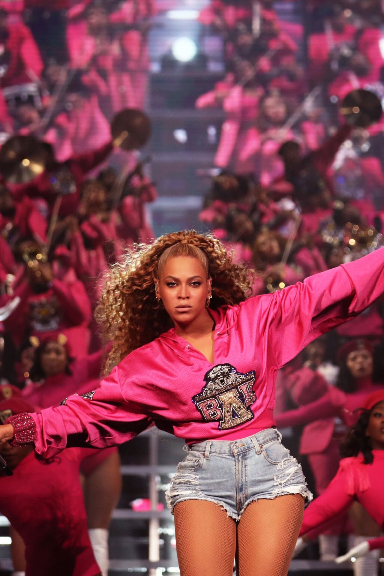 Beyoncé wears a pink sweatshirt and denim shorts while performing on stage. - Beyonce