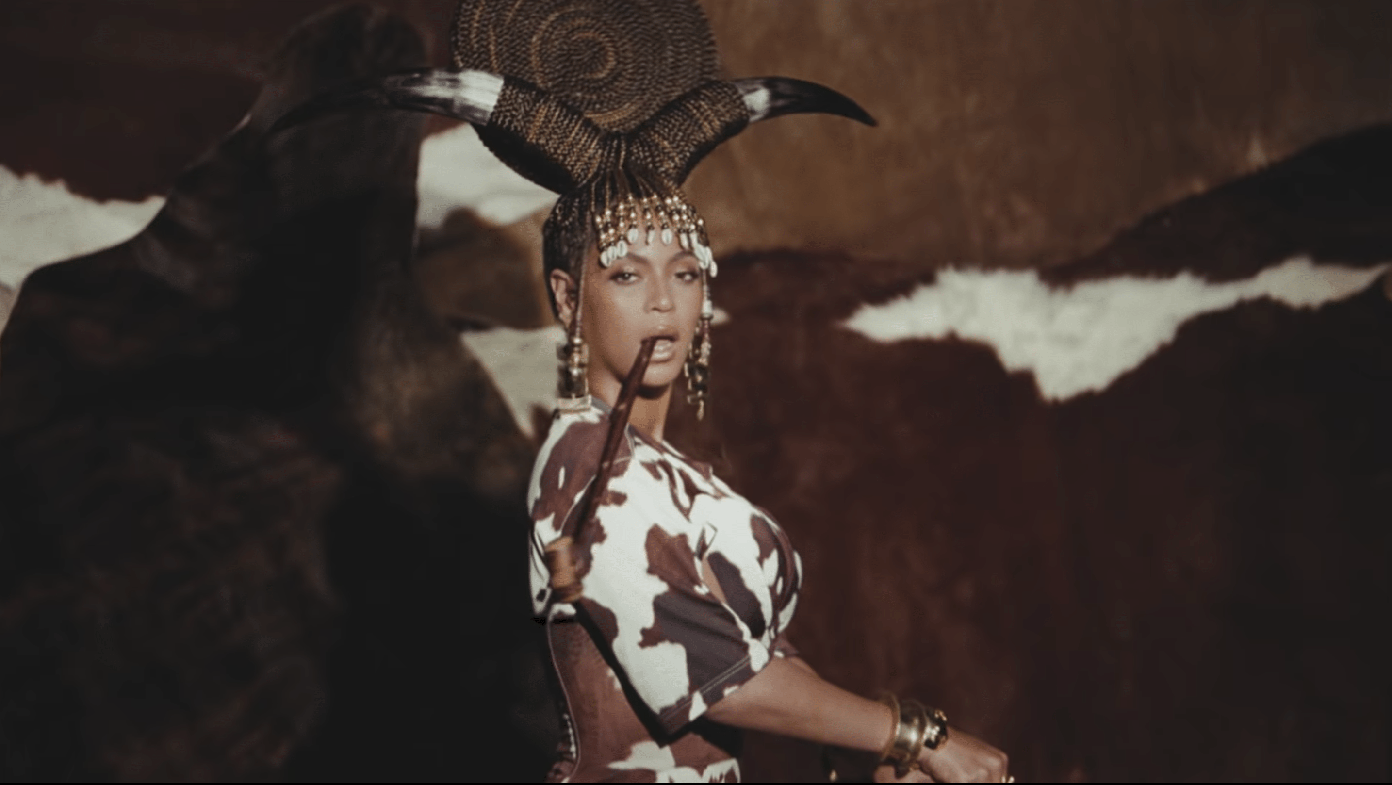 Beyoncé in a horned headdress and cow print dress in the Spirit music video - Beyonce