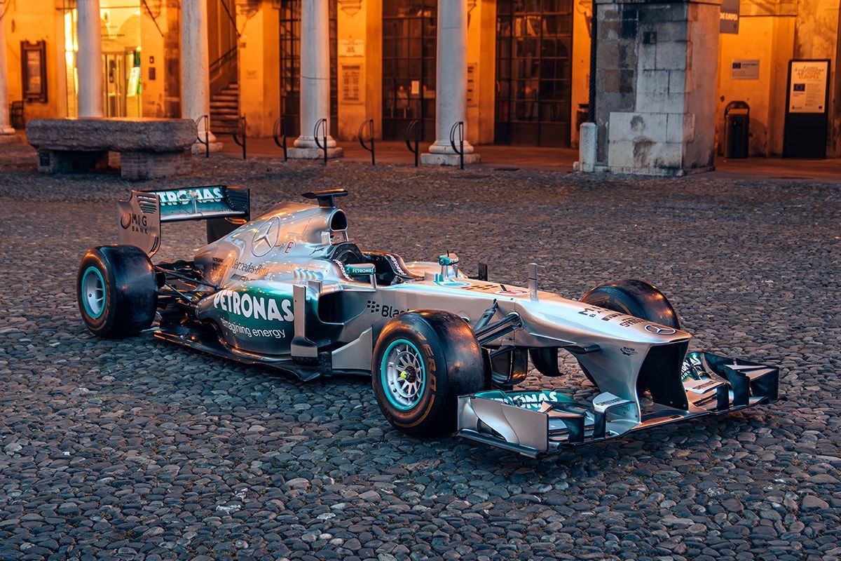 A silver Mercedes F1 car on a cobbled surface in front of a neoclassical building - Lewis Hamilton