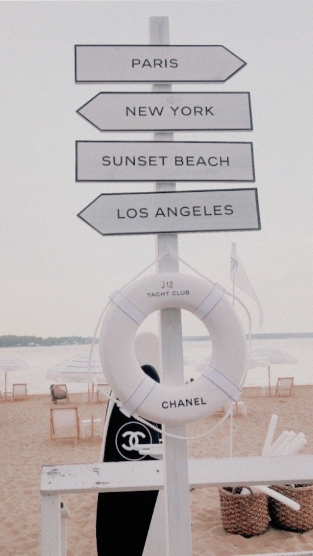 A sign on the beach pointing to different locations - Beach