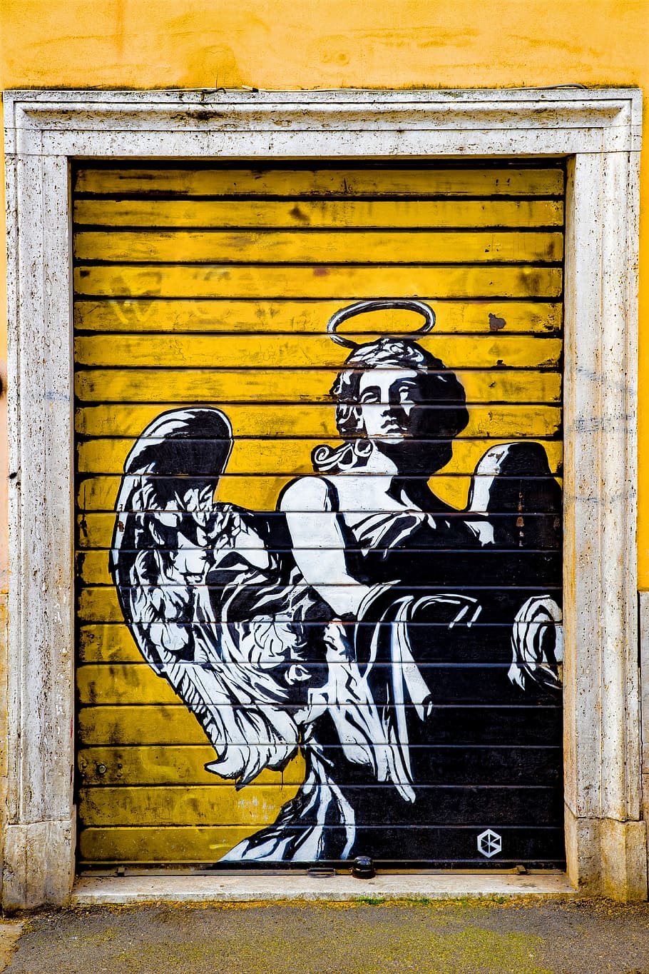 Street art of an angel painted on a yellow garage door in Rome, Italy - Graffiti