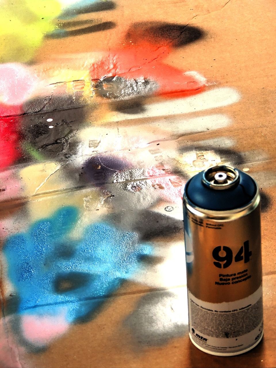 A can of spray paint next to a wall with graffiti on it - Graffiti