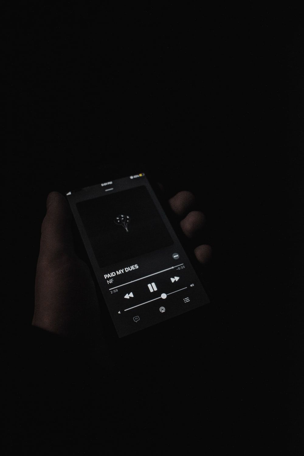 Person holding black smartphone in the dark - Spotify