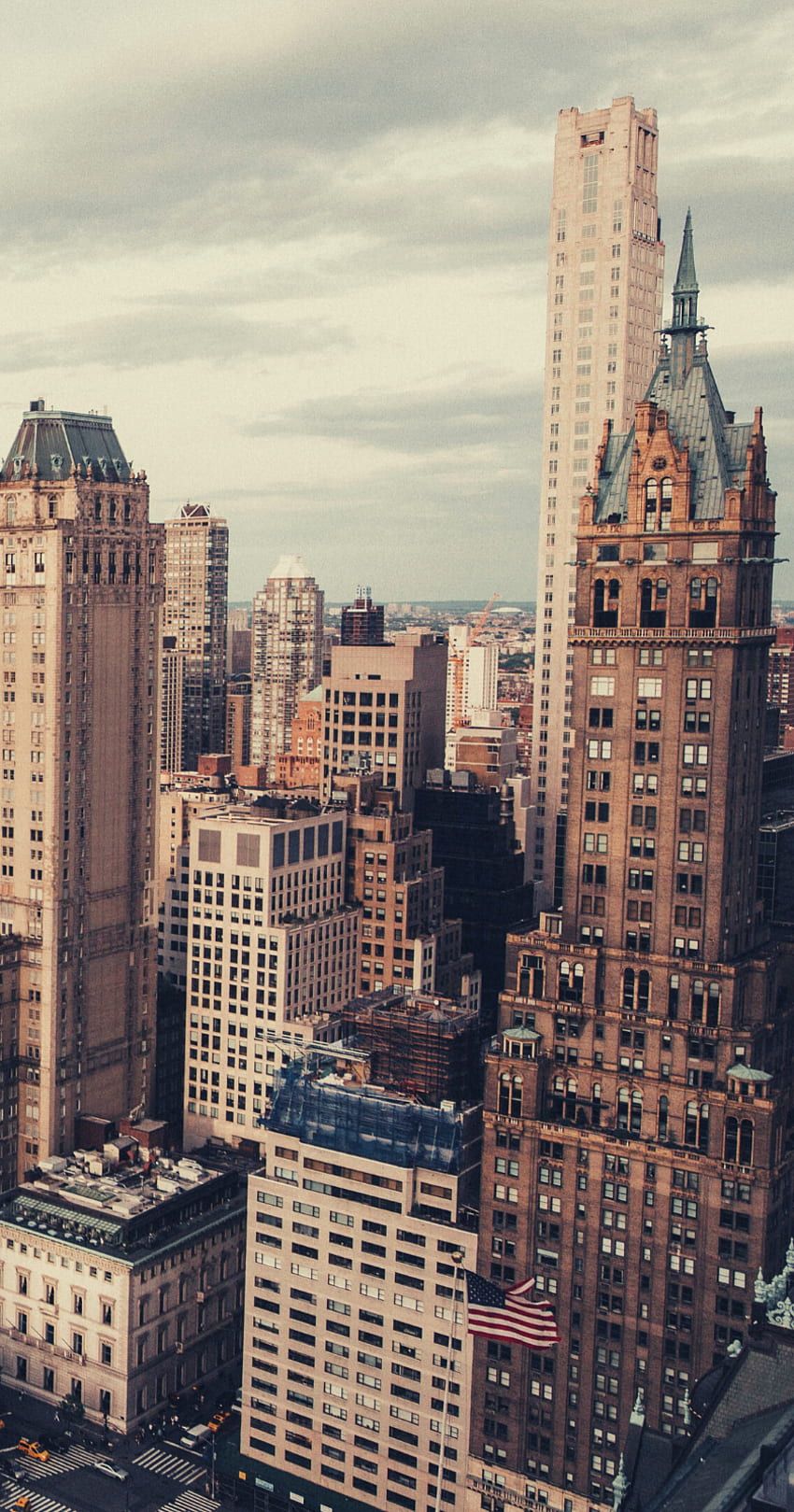 A cityscape of tall buildings with a flag on the top of one of them - New York