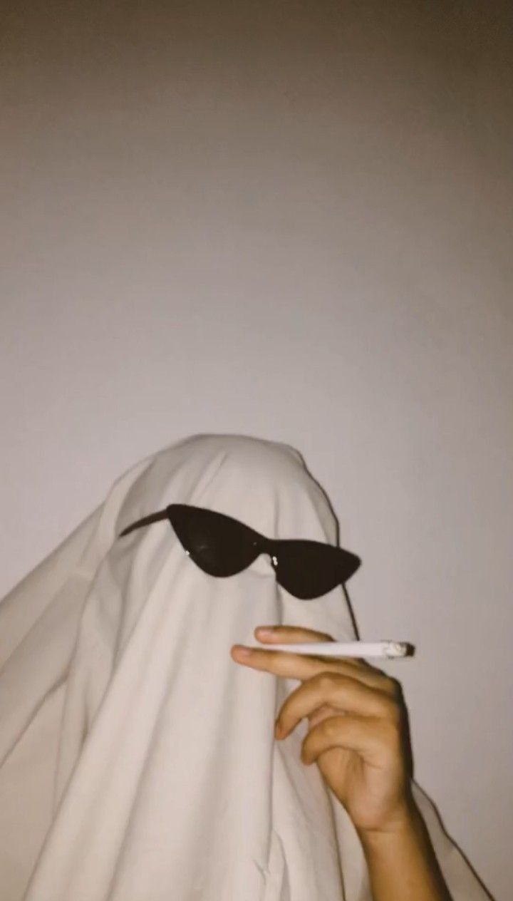 A person in a white sheet with sunglasses and a cigarette. - Ghost